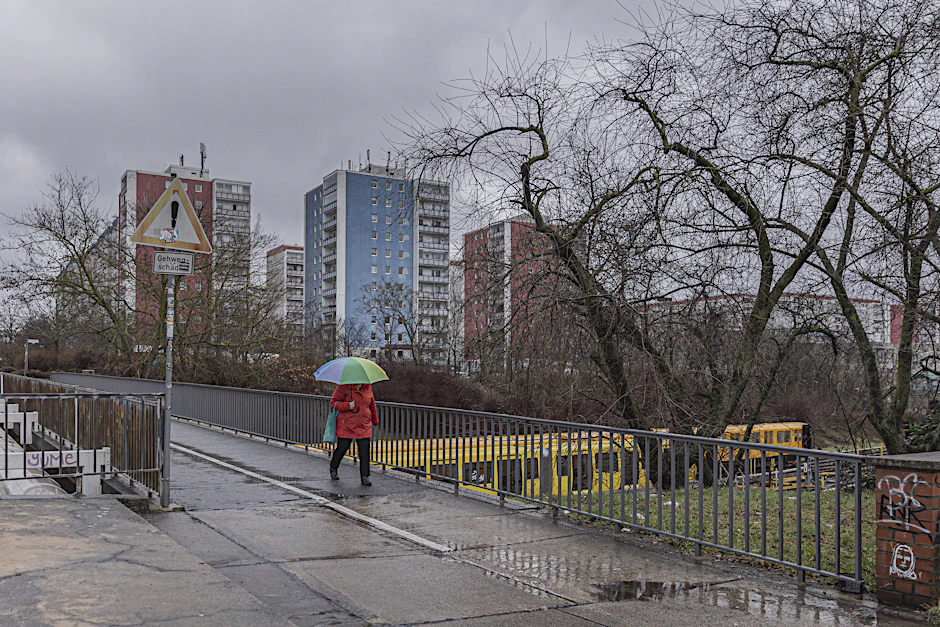 Eine Frau geht über eine Brücke, hinter ihr ein Wohnblock in Hellersdorf. Fremd in der eigenen Stadt zu sein, das fühlt sich für viele nicht gut an.&nbsp;&nbsp;