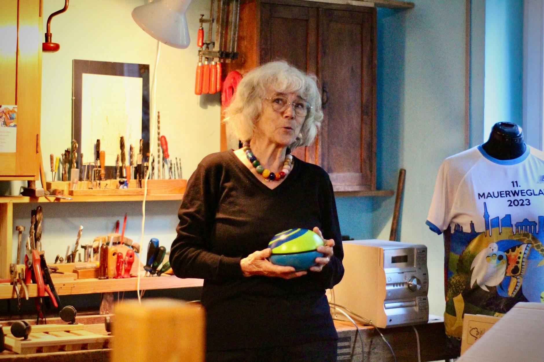 Ursula Wünsch in ihrem Keller vor der Werkbank: Hier schuf sie einst ihre fantasievollen und robusten Spielmittel, umgeben von bunten Kugeln und Werkzeugen.