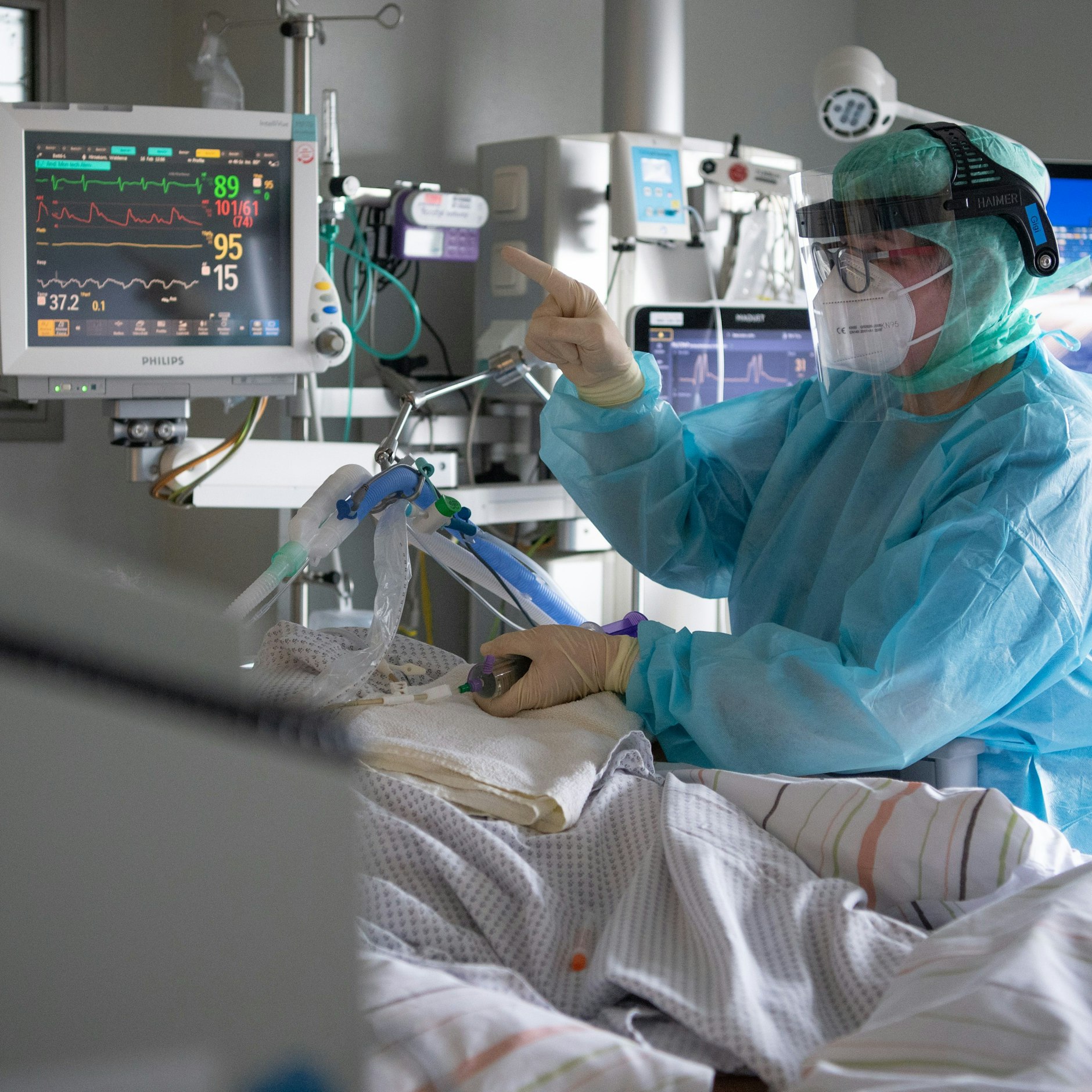 Eine Intensiv-Pflegerin versorgt einen schwer an Corona erkrankten Patienten auf einer Intensivstation.