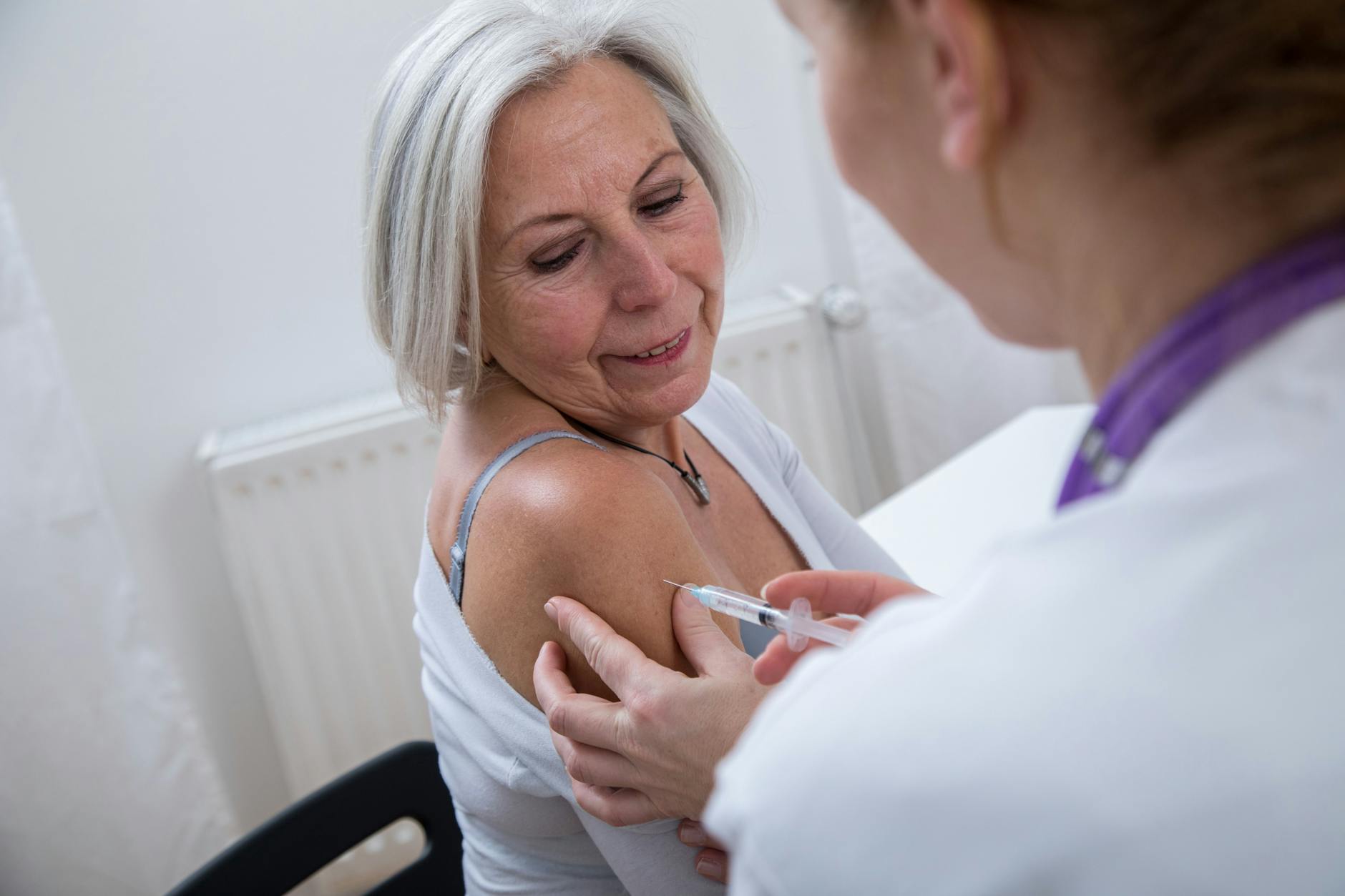 Eine Ärztin impft eine Patientin gegen Influenza.