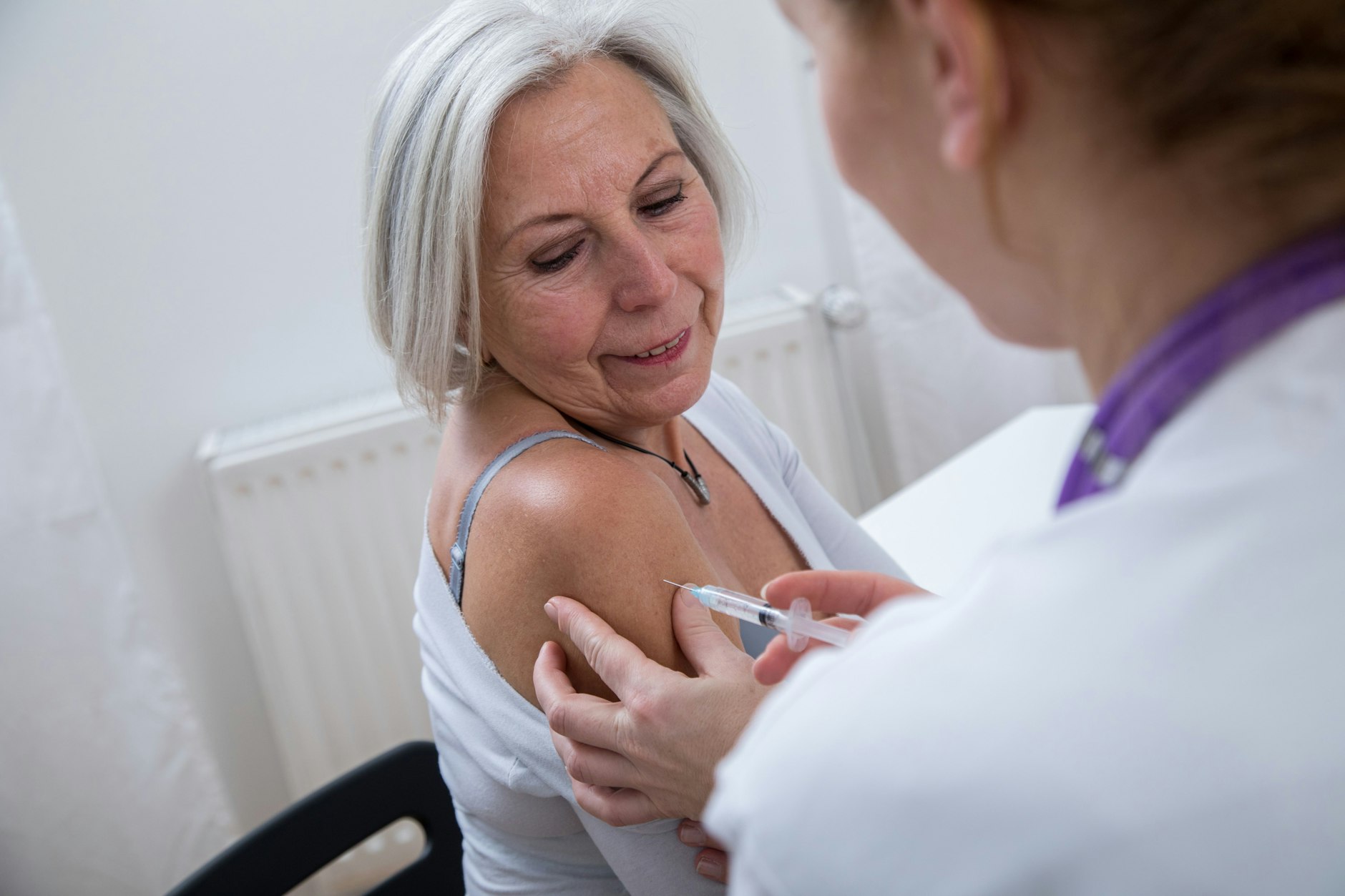 Eine Ärztin impft eine Patientin gegen Influenza.