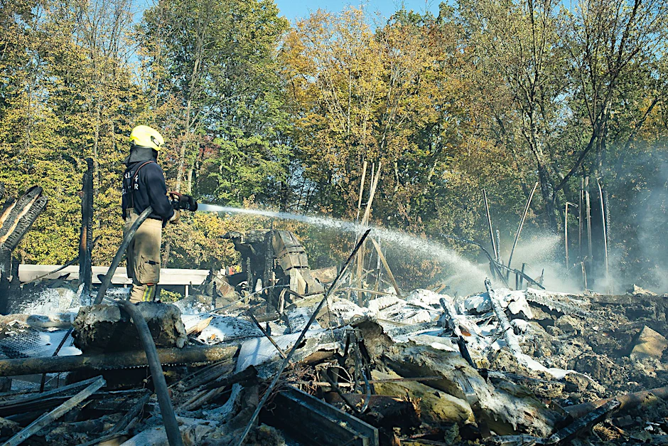 Ein Feuerwehrmann bekämpft die Glutnester in der Brandruine des Umweltbildungszentrums im Britzer Garten.