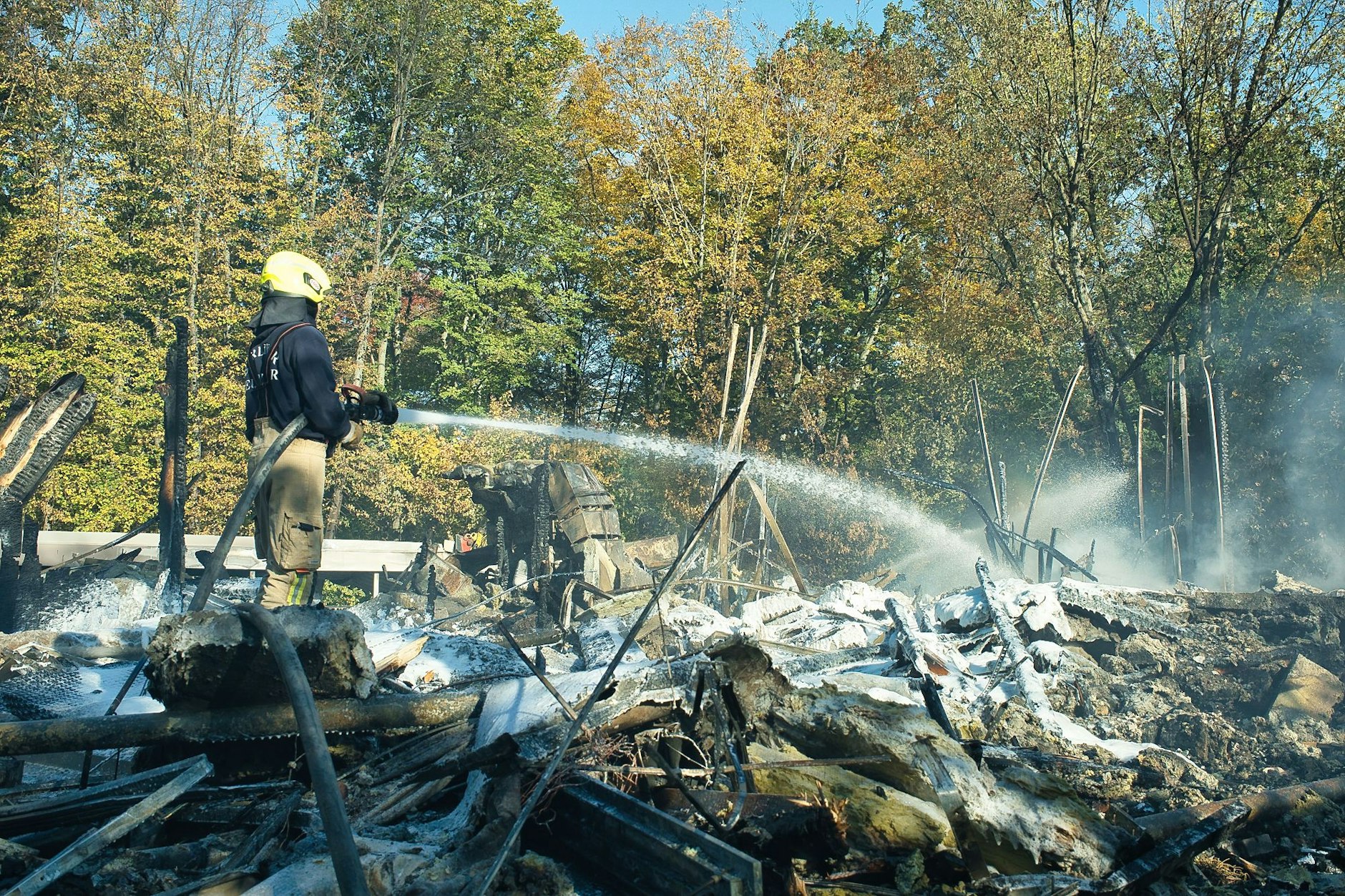 Ein Feuerwehrmann bekämpft die Glutnester in der Brandruine des Umweltbildungszentrums im Britzer Garten.