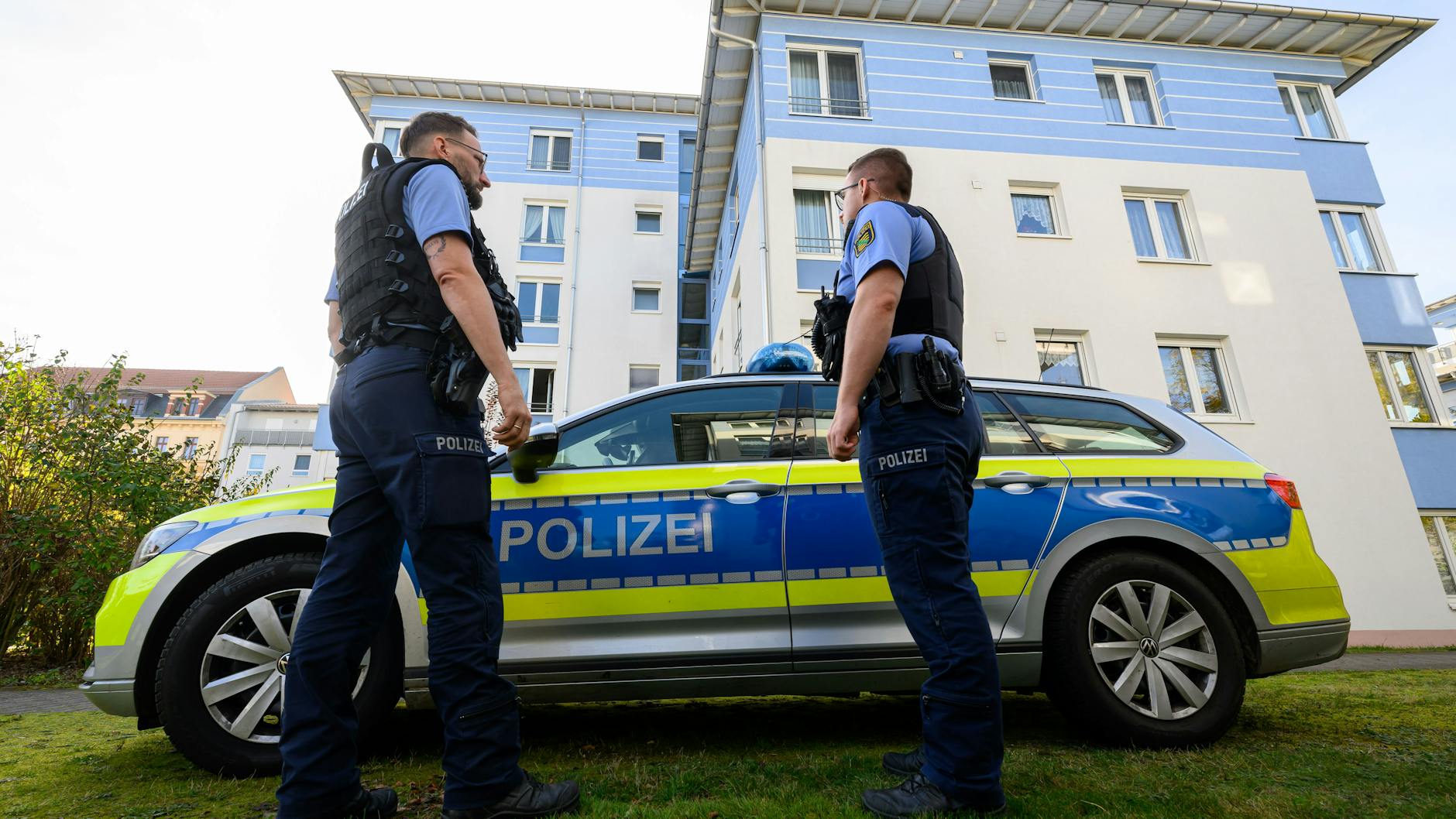 Polizisten stehen vor dem Mehrfamilienhaus in Leipzig, wo die Tat geschehen sein soll.