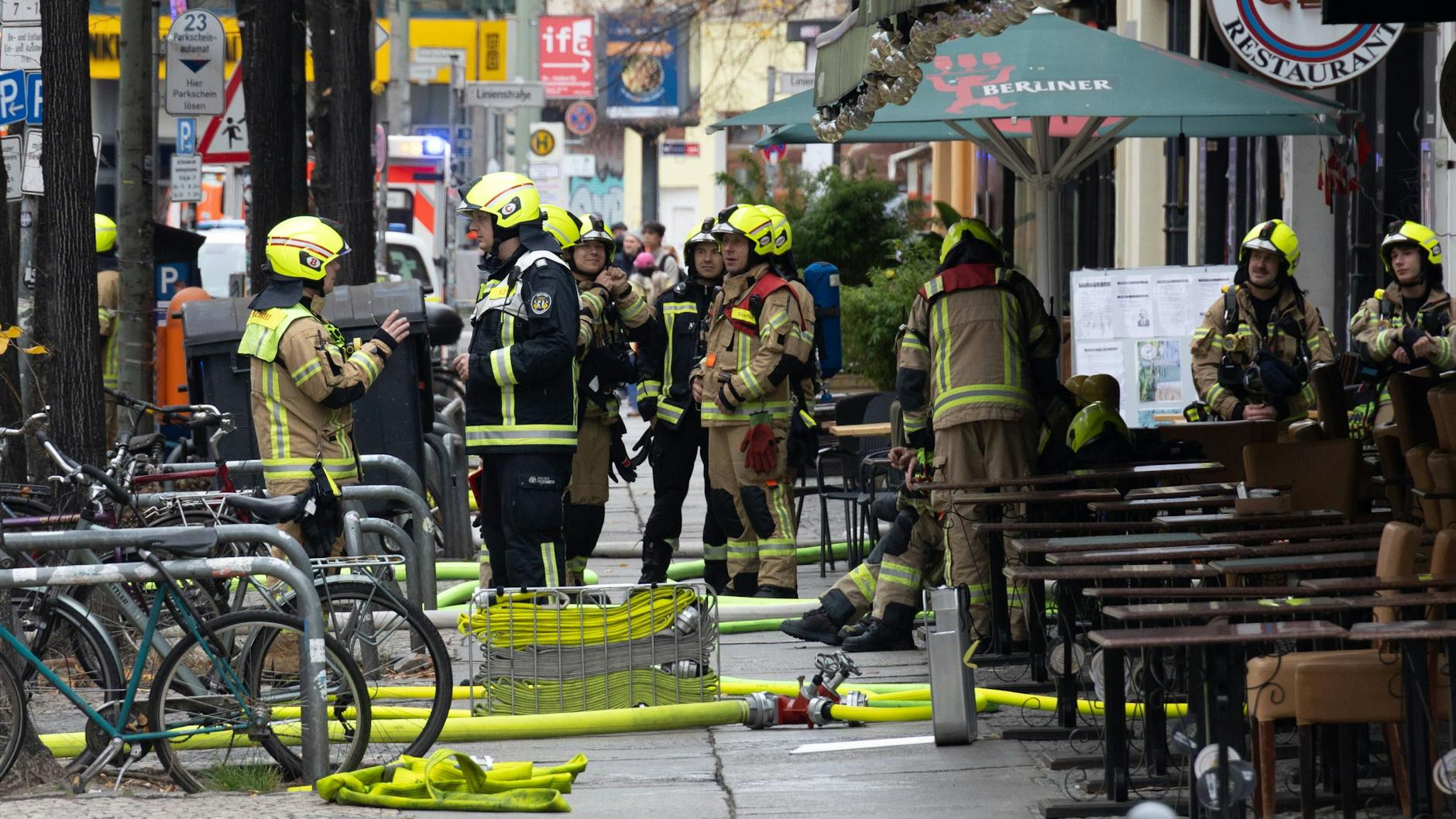 Feuerwehrleute besprechen sich vor dem Gebäude in dem ein Feuer in Mitte ausgebrochen ist.