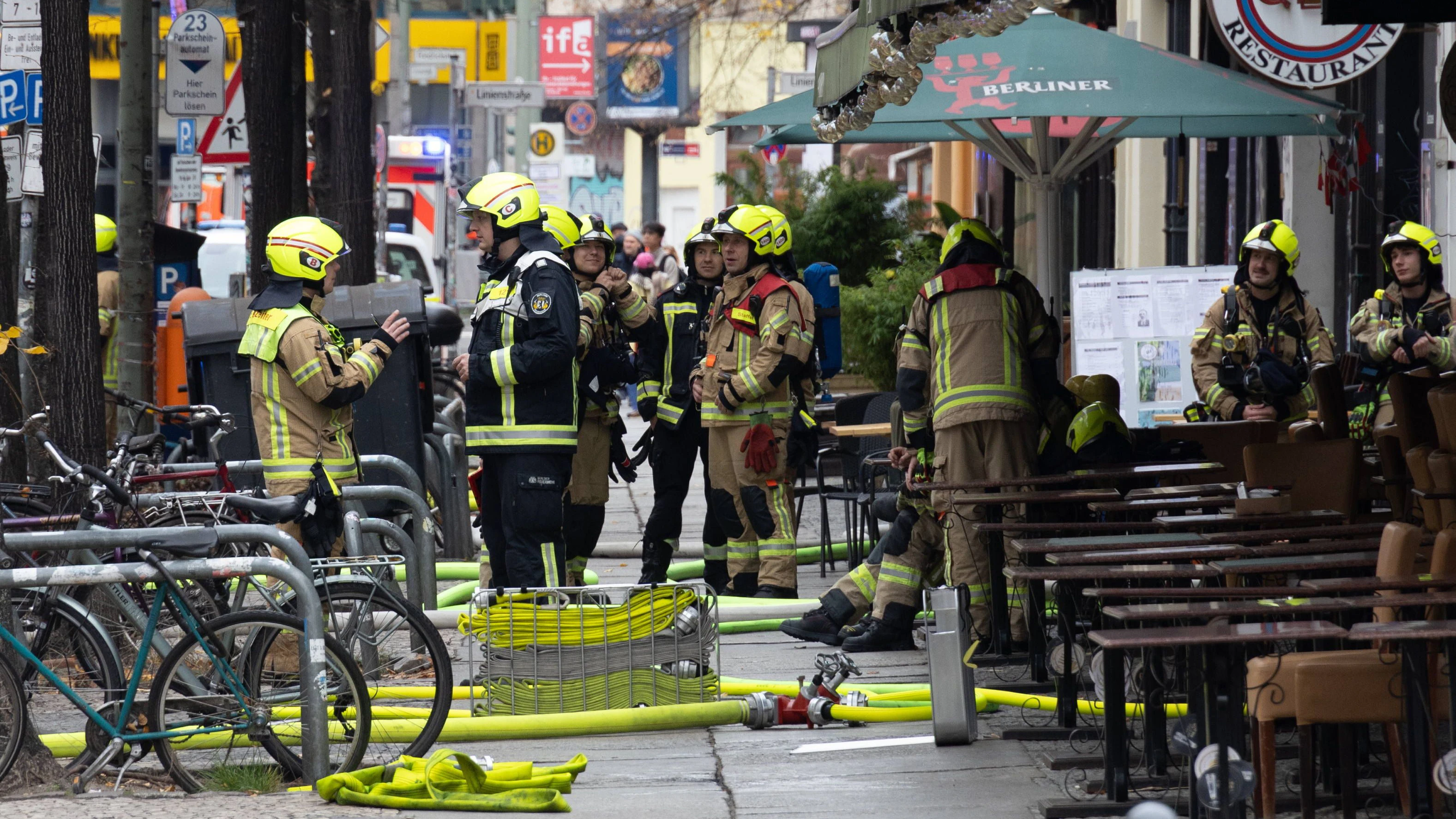 Feuerwehrleute besprechen sich vor dem Gebäude in dem ein Feuer in Mitte ausgebrochen ist.