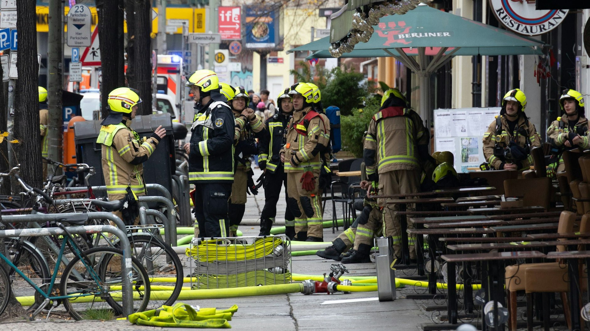 Feuerwehrleute besprechen sich vor dem Gebäude in dem ein Feuer in Mitte ausgebrochen ist.
