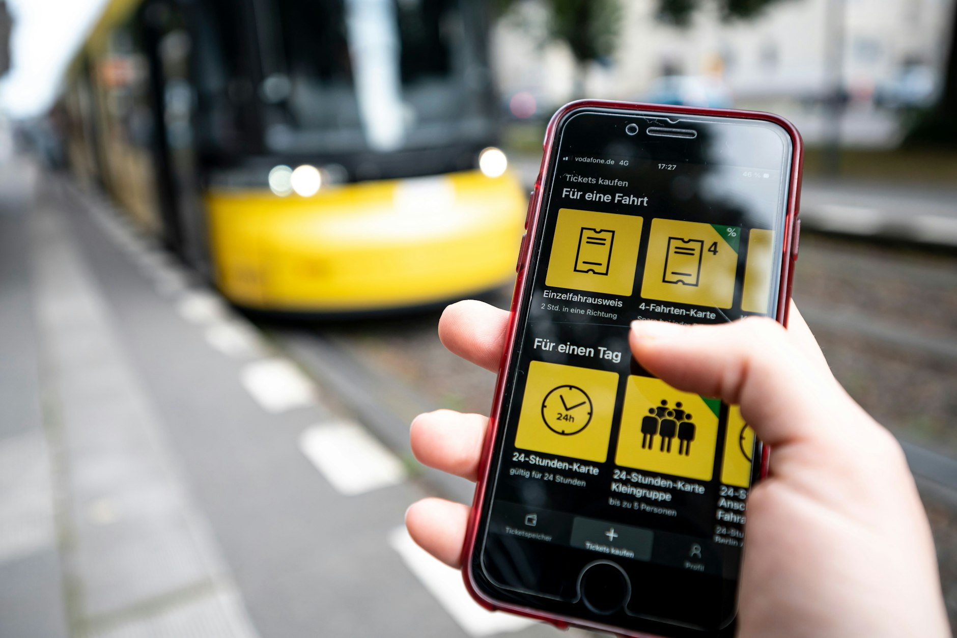 Eine Frau benutzt vor einer einfahrenden Tram die App der Berliner Verkehrsbetriebe (BVG), um sich online eine Fahrkarte zu kaufen. Das wird ab 2025 noch teurer.&nbsp;