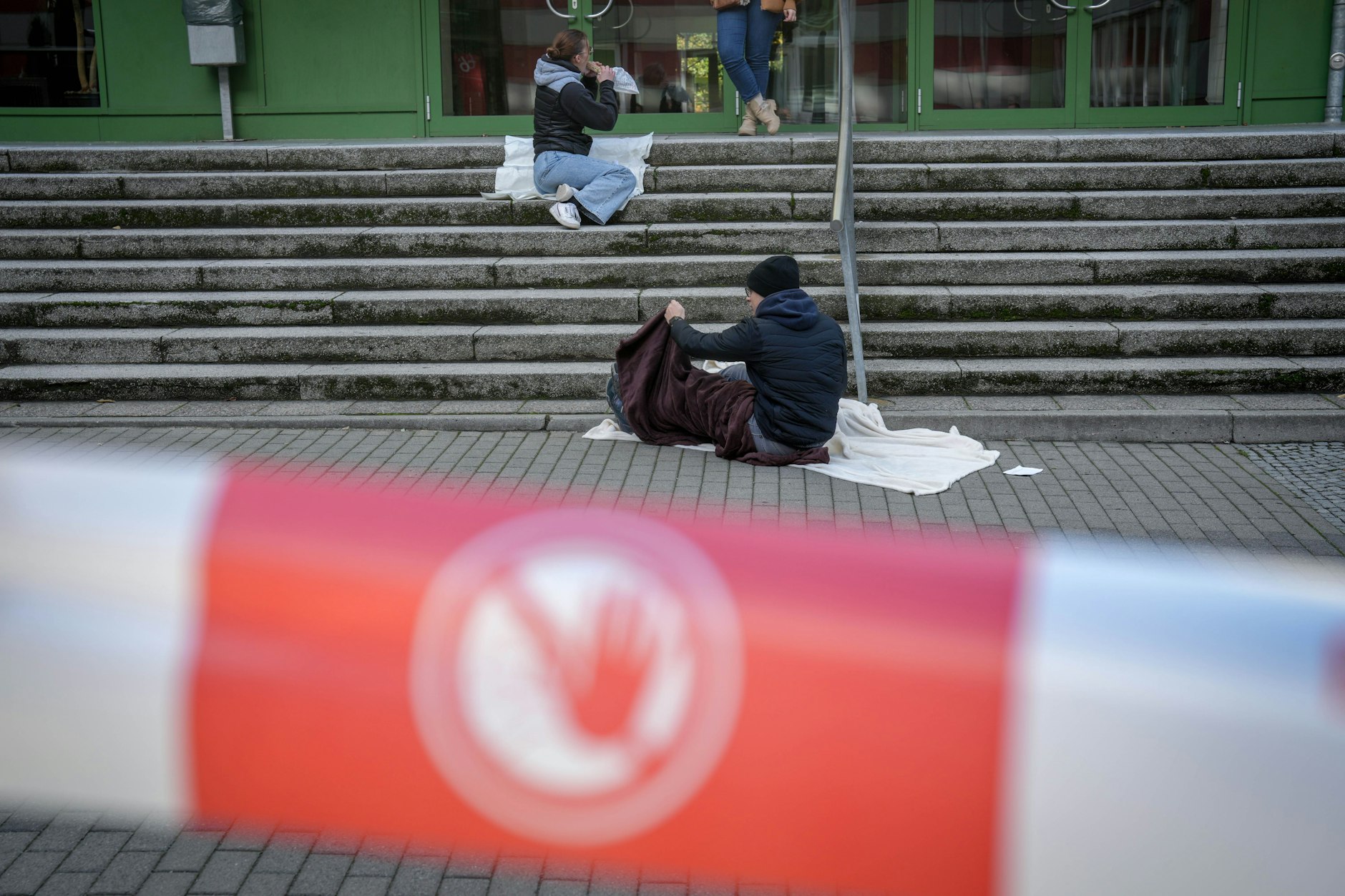 Darsteller sitzen in einem Übungsszenario für eine Katastrophenschutzübung auf dem Boden vor der Hochschule für Wirtschaft und Recht.