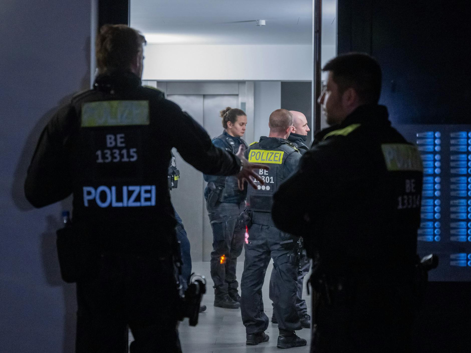 Polizisten stehen vor einem Mehrfamilienhaus im Stadtteil Marzahn.