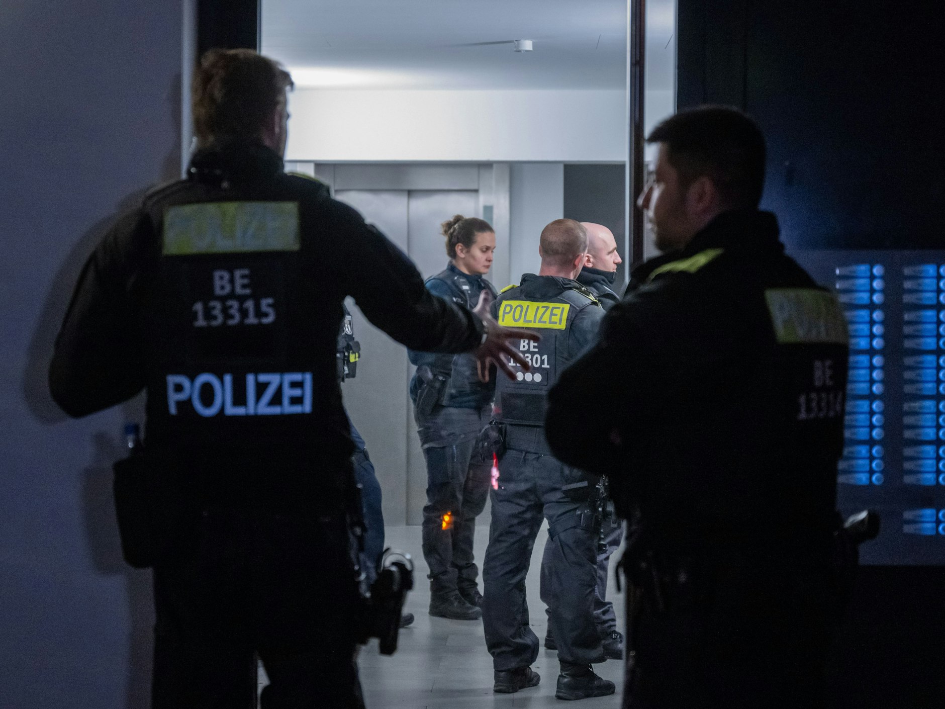 Polizisten stehen vor einem Mehrfamilienhaus im Stadtteil Marzahn.