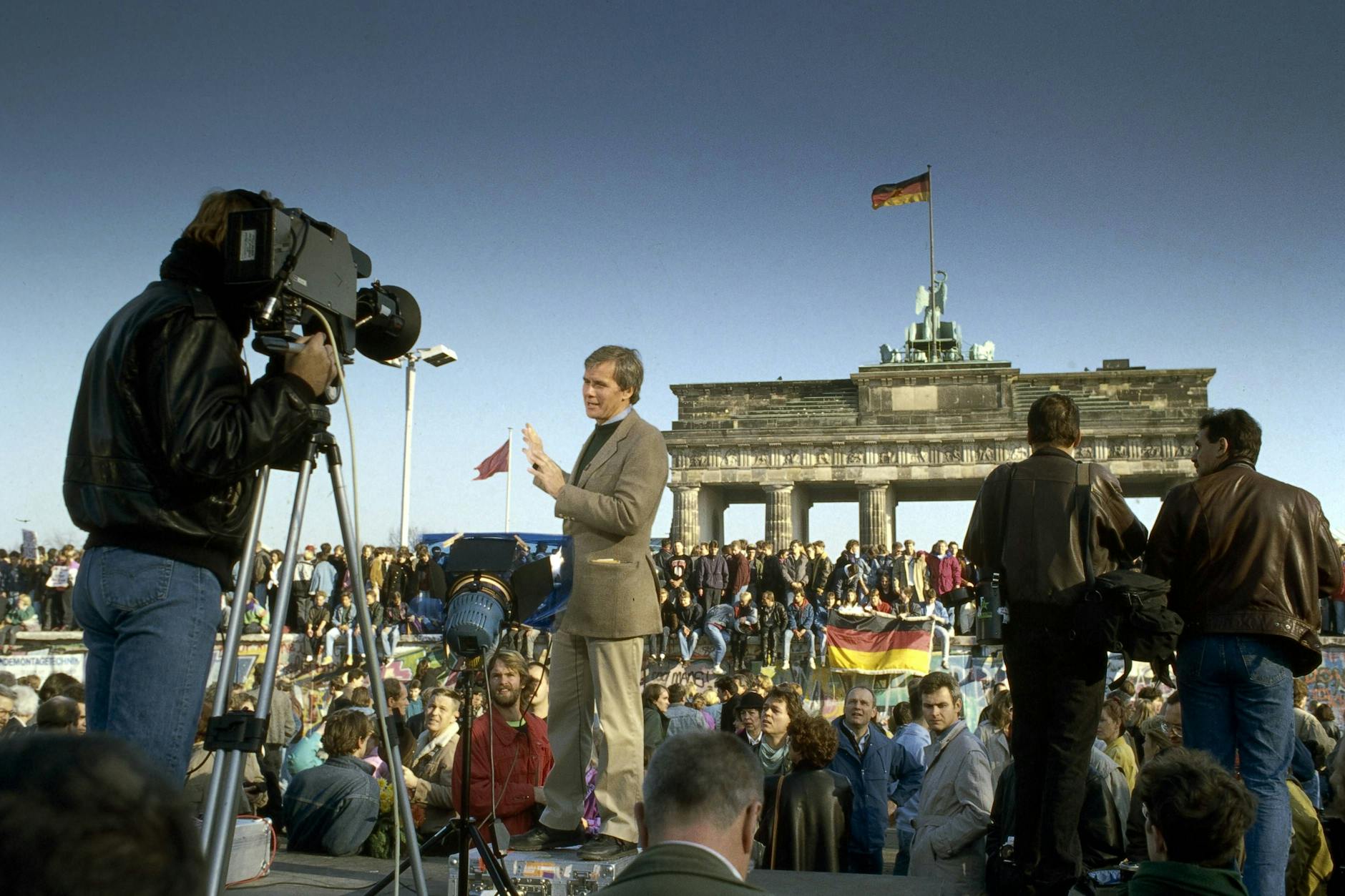 Ein TV-Moderator und Menschen aus Ost und West feiern den Fall der Berliner Mauer vor dem Brandenburger Tor in Berlin. (Archiv)