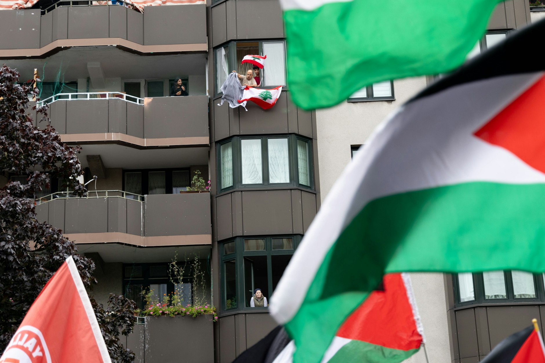 6.10.2024: Ein Mann weht vom Balkon eines Mietshauses mit einer Kufiya Palästinensertuch und libanesischer Flagge während pro-Palästinensische Demonstranten protestieren am Kottbusser Tor in Berlin-Kreuzberg unter dem Motto - Demo gegen Genozid in Gaza. (Archivfoto)