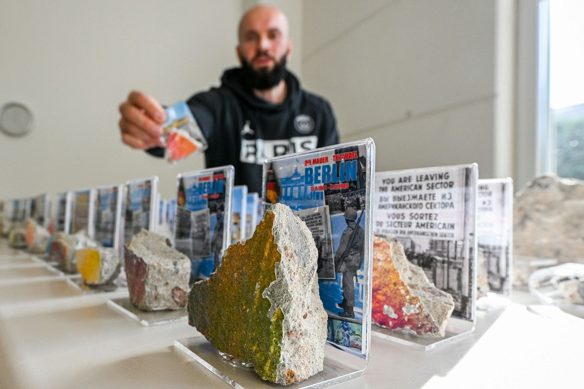 18.10.2024, Berlin: Julian Sacha, Geschäftsführer der Urban Products Sacha GmbH, beliefert Souvenirläden und Sammler in aller Welt mit originalen Mauerstücken, die in der Firma in Handarbeit zerkleinert und für den Versand fertig gemacht werden.