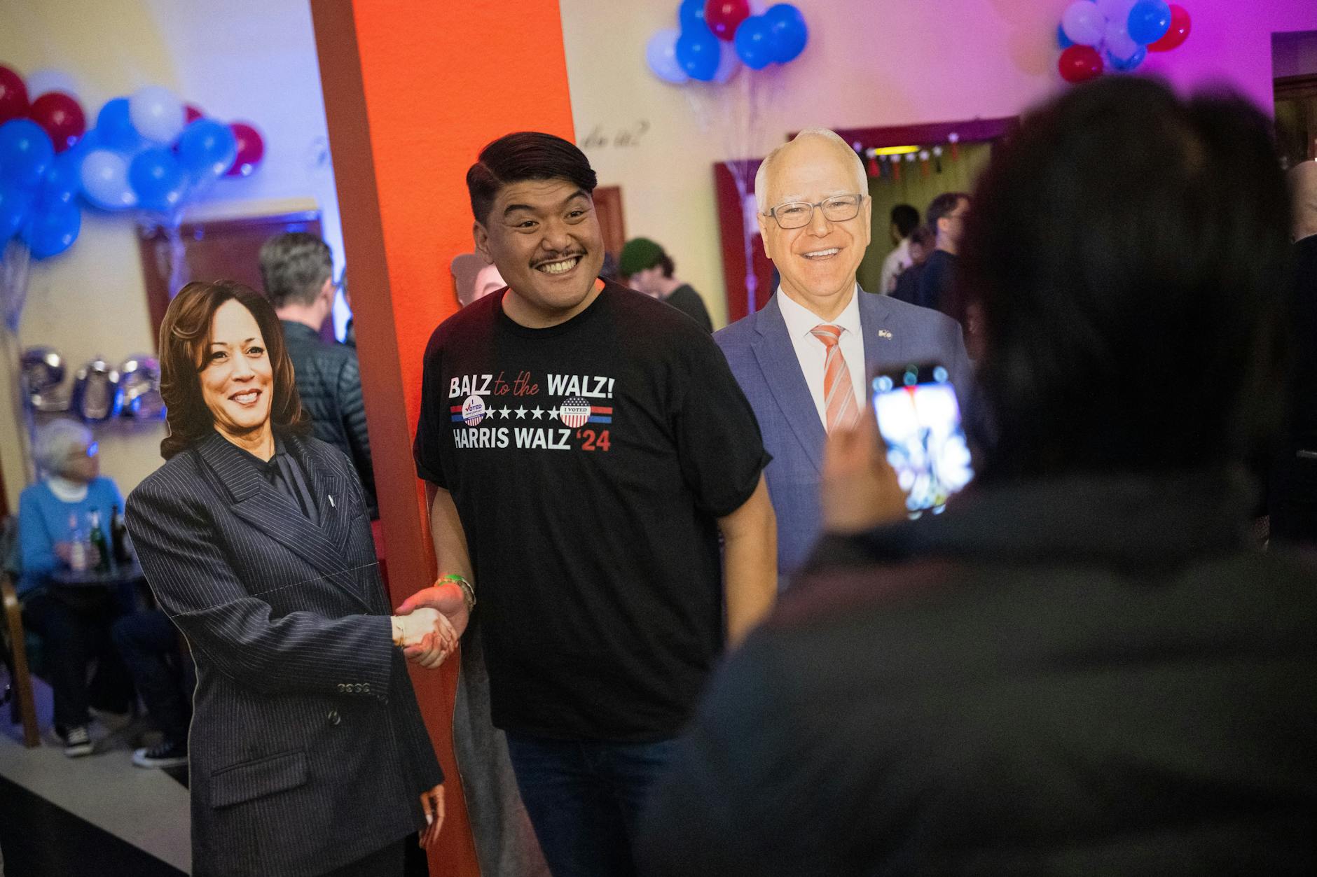 05.11.2024, Berlin: Adonis macht während der Democrats Abroad Election Night im Kino Babylon ein Foto mit den Papp-Aufstellern vom demokratischen Kandidatenduo Harris (l) und Walz.