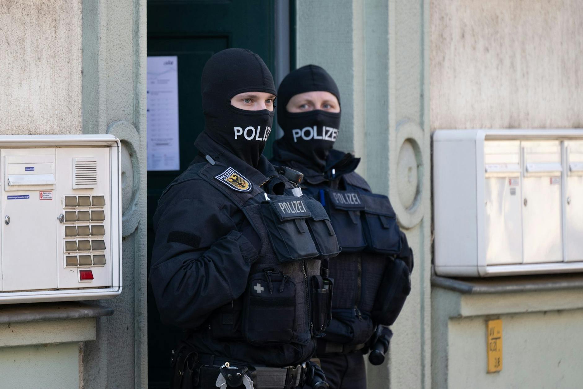 Polizisten stehen während einer Razzia gegen mutmaßliche Rechtsextreme in einem Hauseingang im Dresdner Stadtteil Cotta.