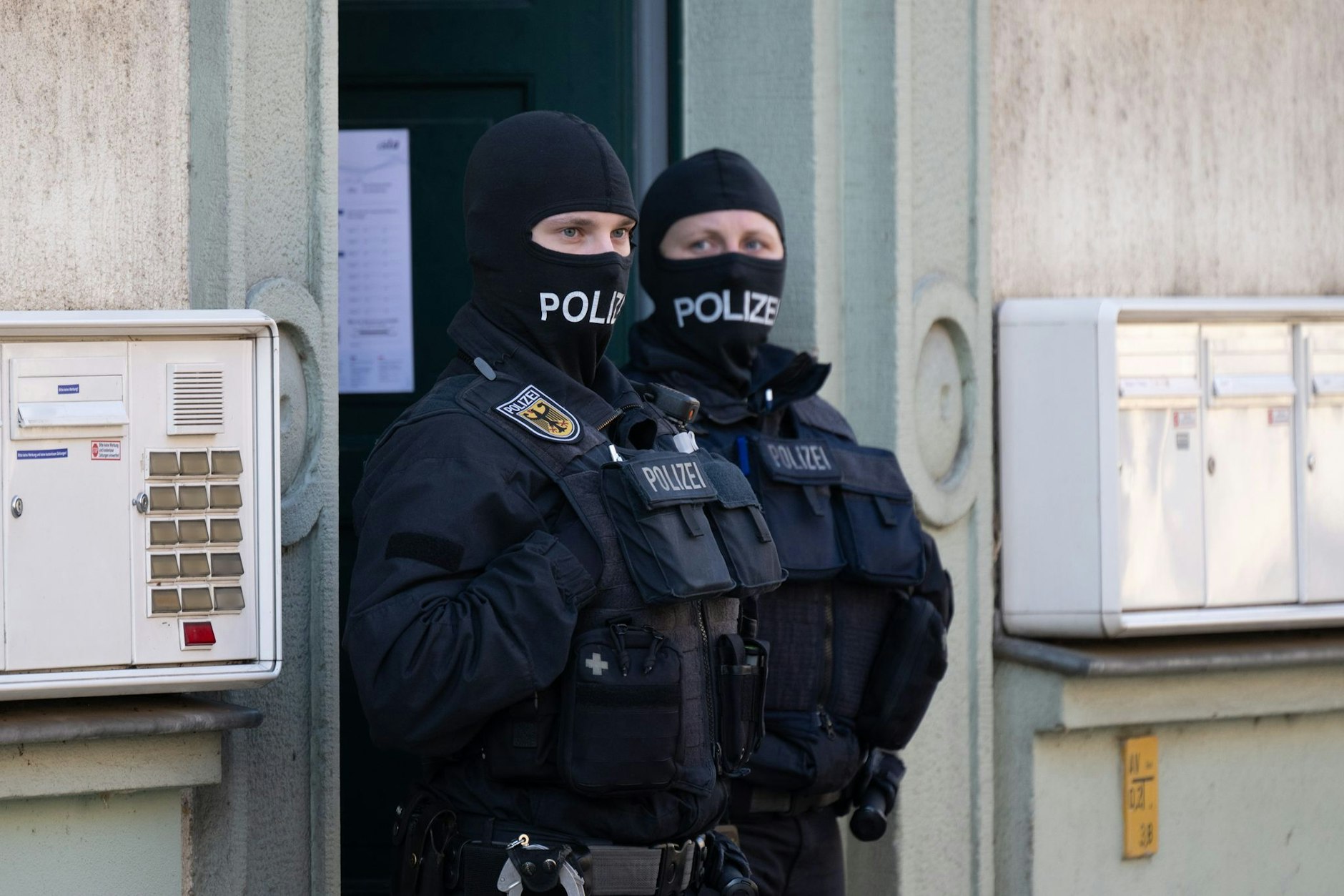 Polizisten stehen während einer Razzia gegen mutmaßliche Rechtsextreme in einem Hauseingang im Dresdner Stadtteil Cotta. 
