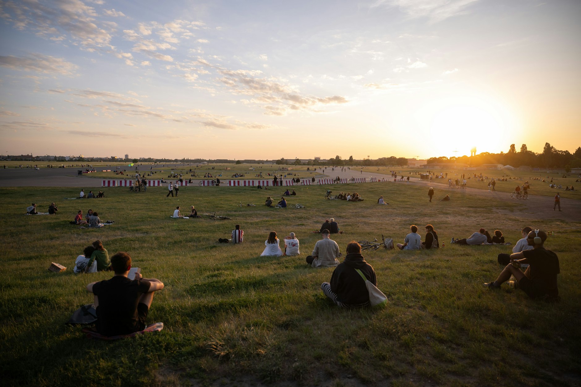 Weite mitten in der Stadt: Menschen sitzen auf dem Tempelhofer Feld. Die Grünflächen könnte für eine Randbebauung genutzt werden.