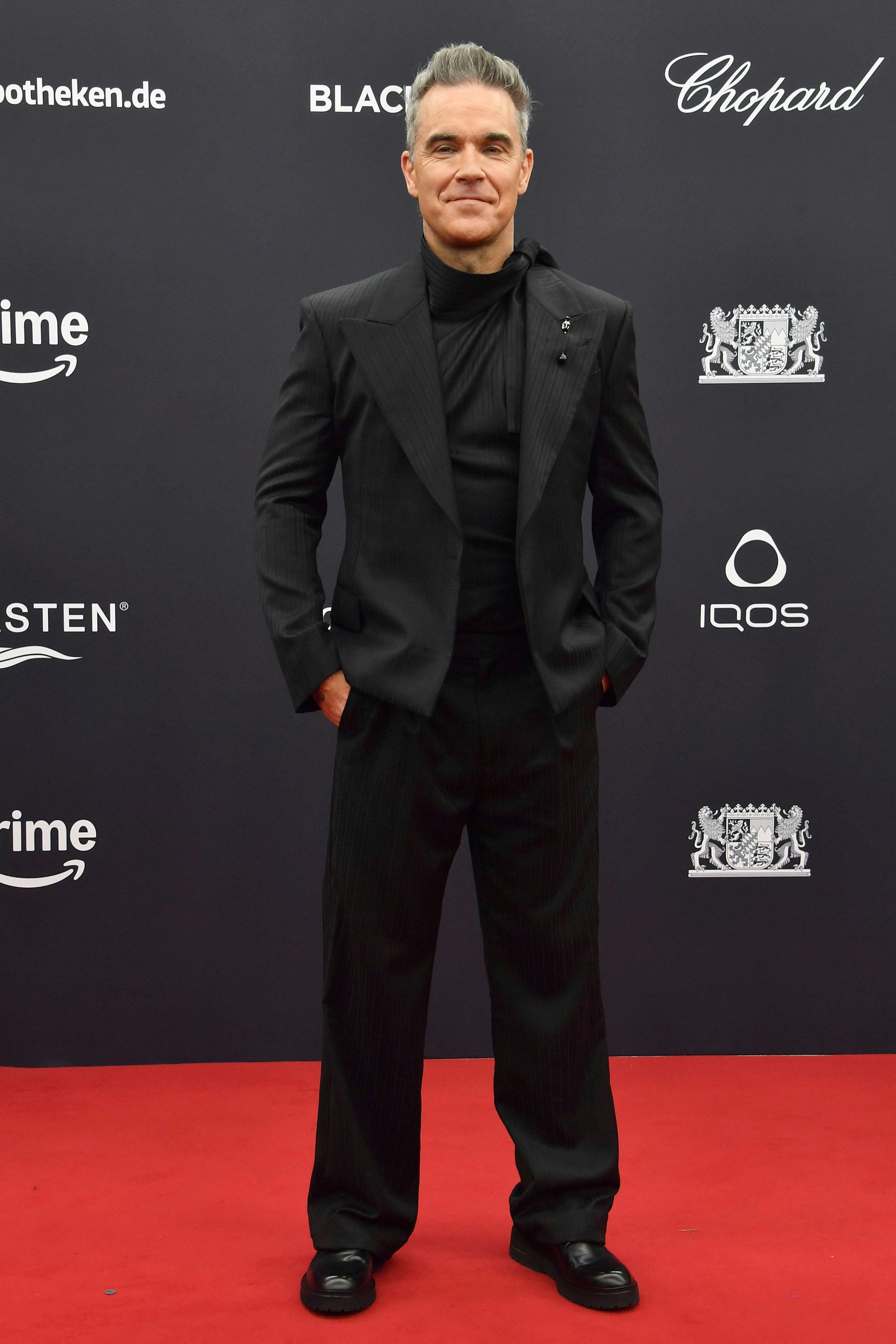 <strong>TOP:</strong> Zugegeben, dass <strong>Robbie Williams</strong> als eine Art internationaler Stargast angekündigt wurde, entlockte uns zunächst nur ein müdes Gähnen. Nur mal so: „Let Me Entertain You“ ist aus dem Jahr 1997. Doch dann dieser Auftritt, zack, da waren wir doch glatt wieder hellwach! Die Boygroup-Tolle sieht in Grau äußerst apart aus, das spitzbübische Lächeln funktioniert noch immer und der Anzug von Emporio Armani tut wirklich sehr viel für ihn, wie Guido Maria Kretschmer sagen würde. Die Hose lässig ausgestellt, das Sakko eng auf Taille, dazu ein schwarz schimmerndes, elegant gerafftes Shirt und ein dezentes Schmuckdetail – für uns an diesem Abend einer der bestaussehenden Männer auf dem Bambi-Teppich.