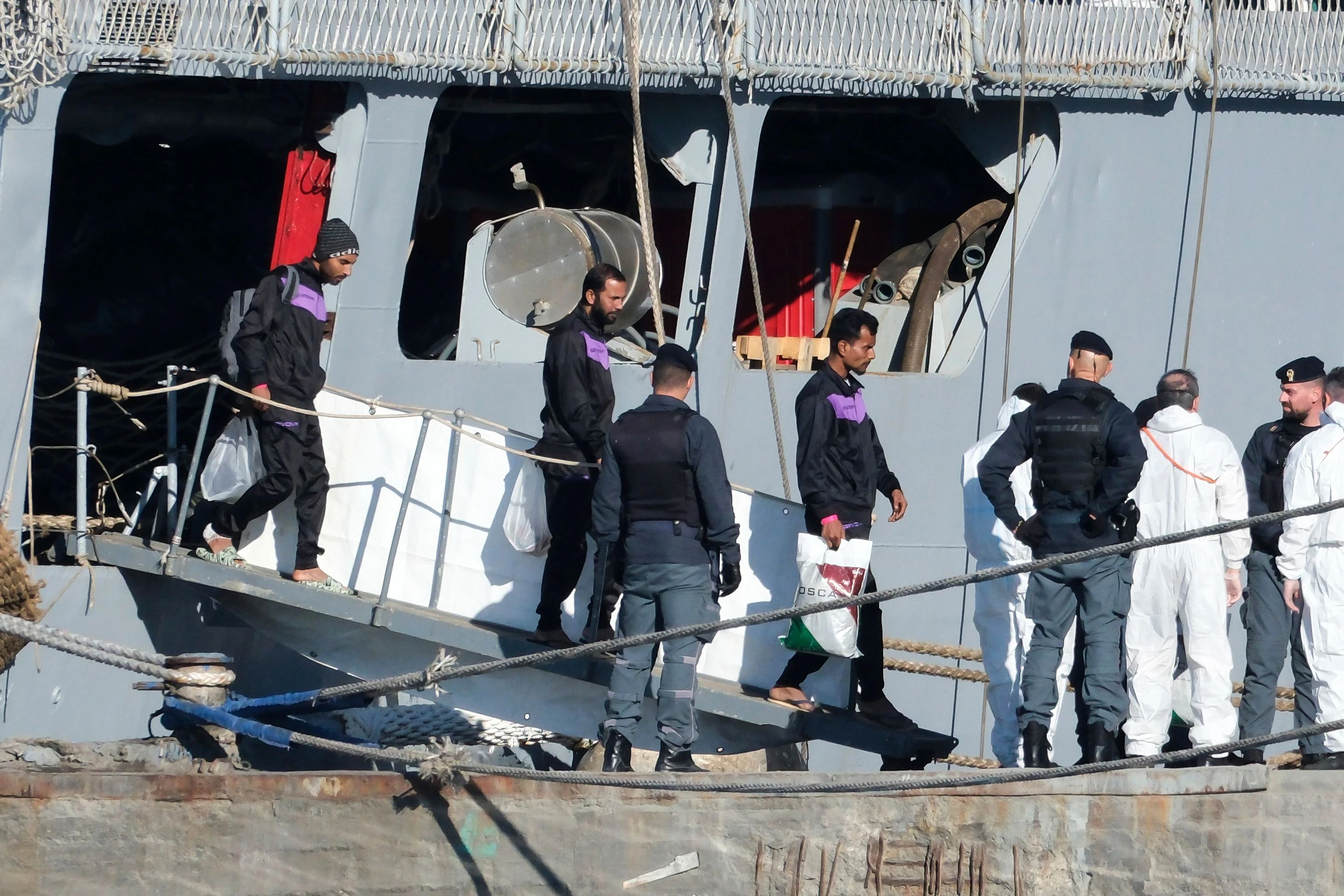 Migranten gehen im Hafen von Shengjin von Bord des italienischen Marineschiffs „Libra“.