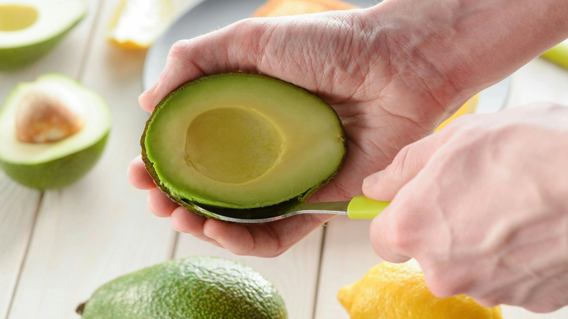 Mit einem Löffel vorsichtig das Fruchtfleisch der Avocado von der Schale lösen.