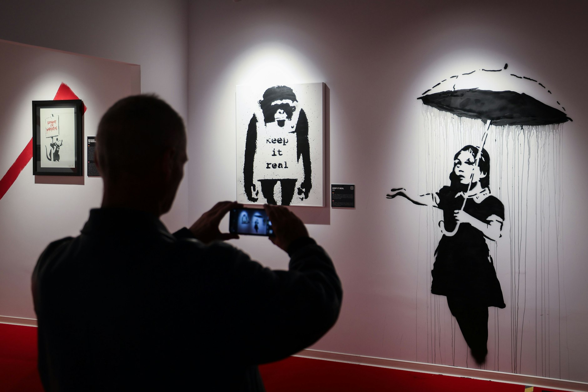Hamburg: Ein Mann fotografiert echte Banksy-Bilder in der Ausstellung „House of Banksy“.