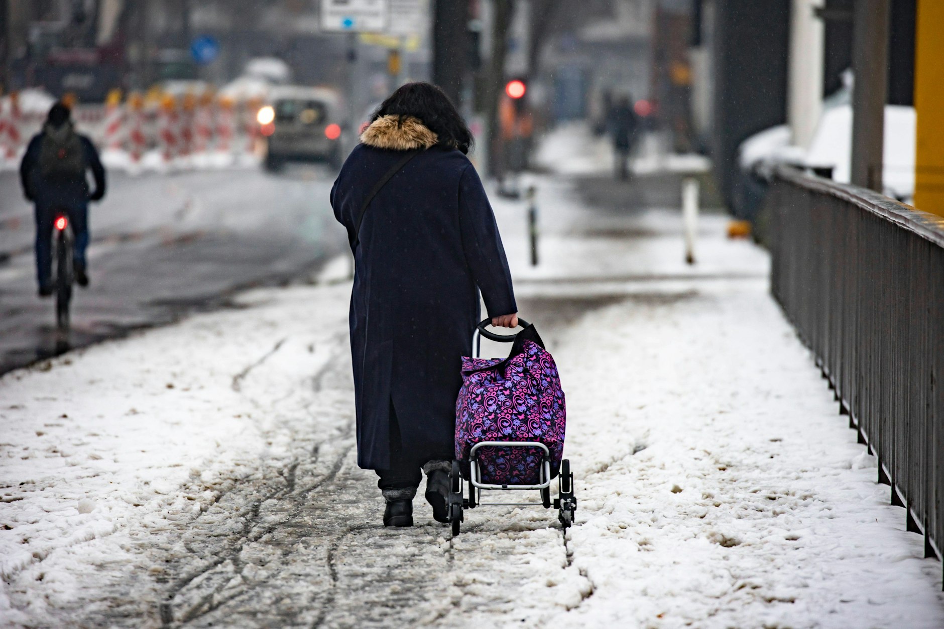 Schmuddelwinter in Berlin im vergangenen Jahr: Eine Frau zieht einen Einkaufstrolley über einen verschneiten Weg.