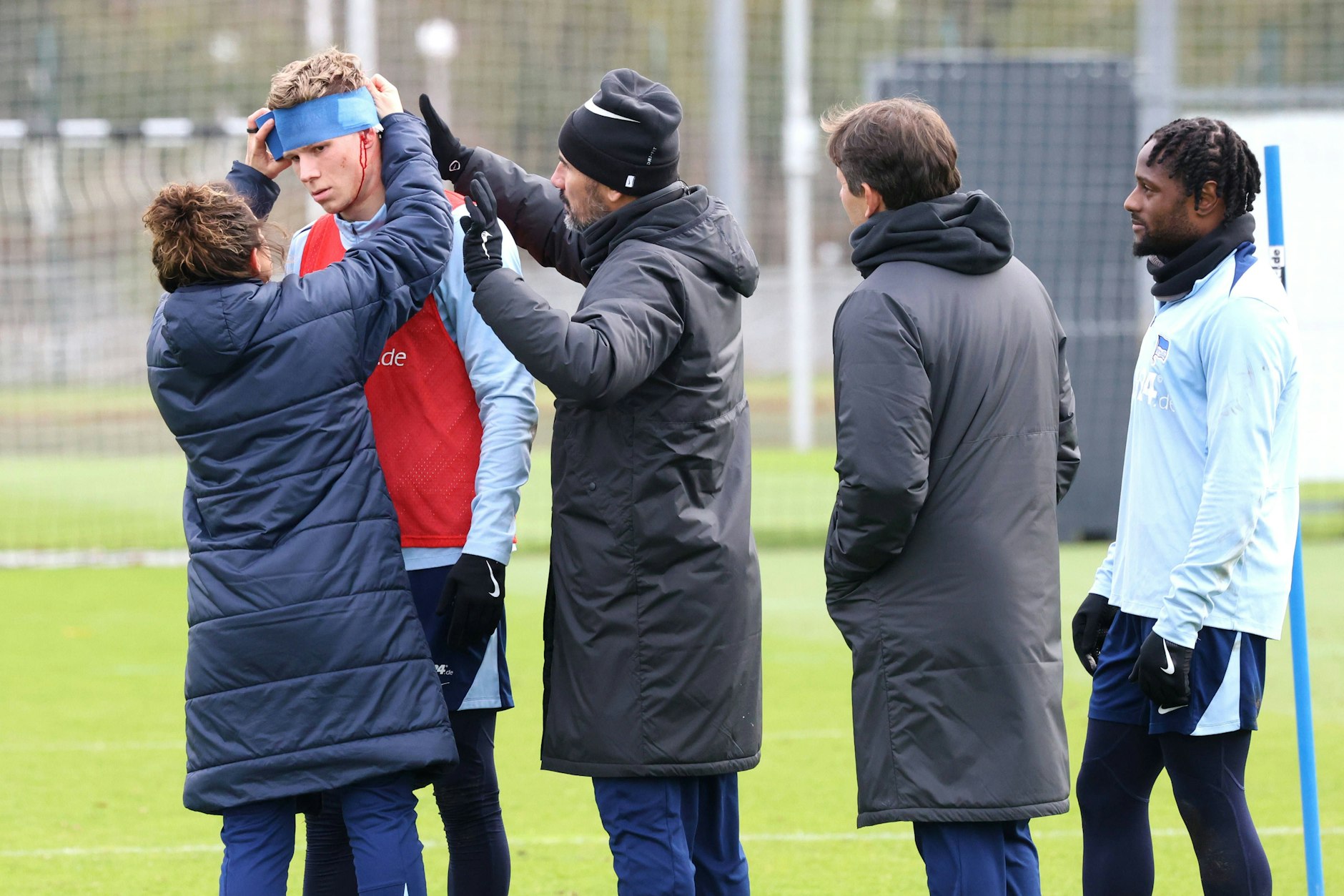 Hertha-Stürmer Luca Schuler bekommt von Physiotherapeutin Anne Kaube einen Turban. Er war mit Deyo Zeefuik (r.) im Training zusammengerasselt.