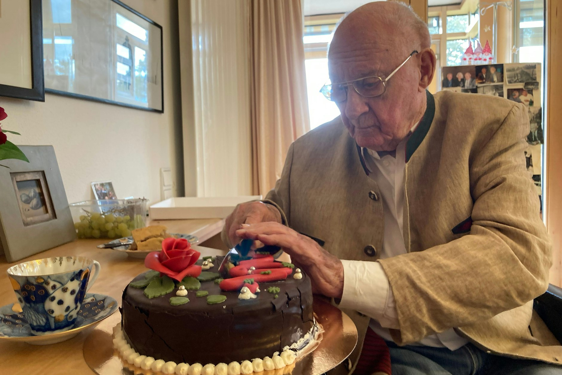 Rolf Schimpf schneidet in seinem Altenheim eine Sachertorte an, die er zu seinem 100. Geburtstag geschenkt bekommen hat.