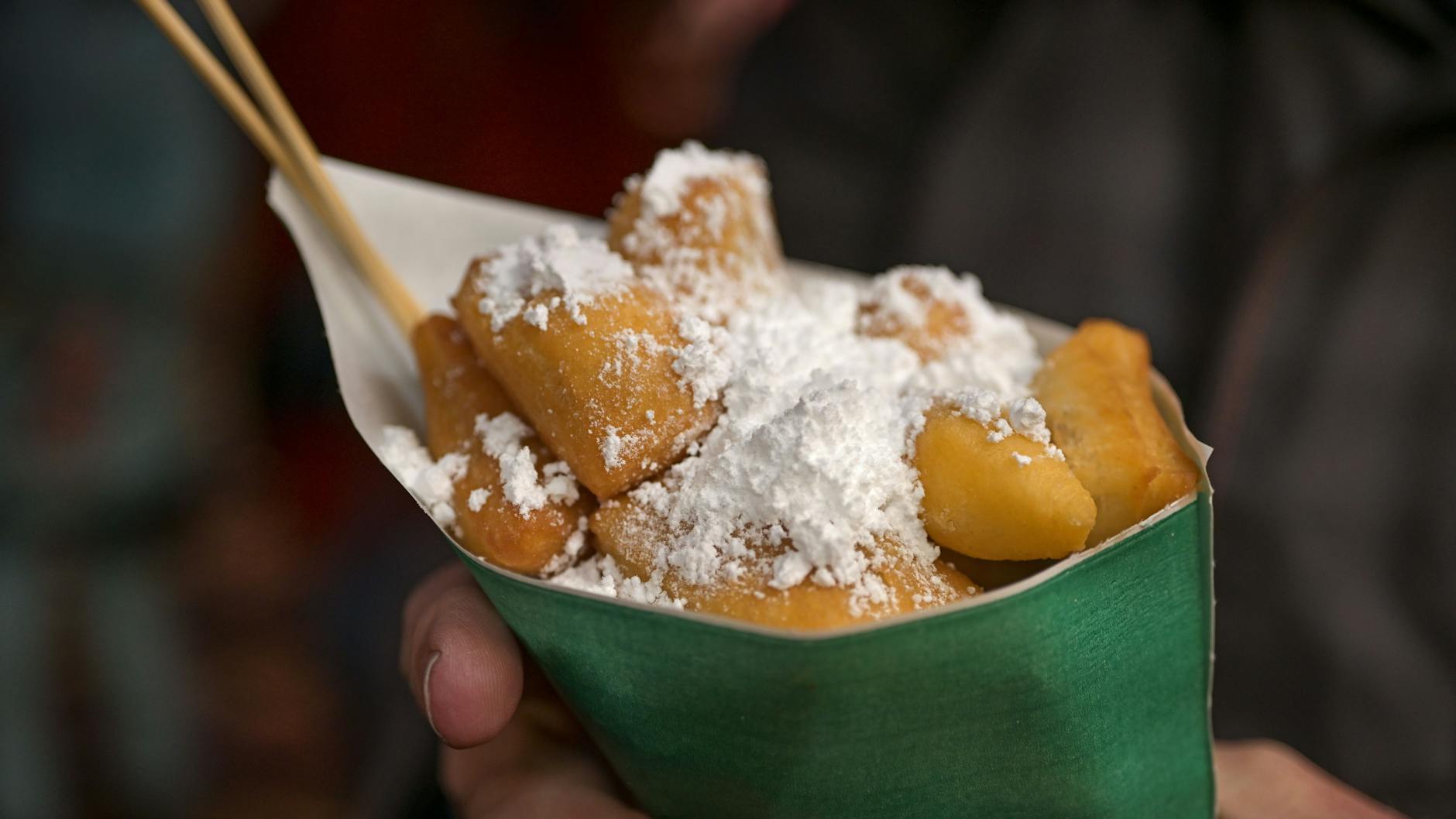 So kennt man sie vom Weihnachtsmarkt: Leckere Kräppelchen in einer Tüte mit einer ordentlichen Portion Puderzucker. Die Nascherei können Sie auch zu Hause backen.