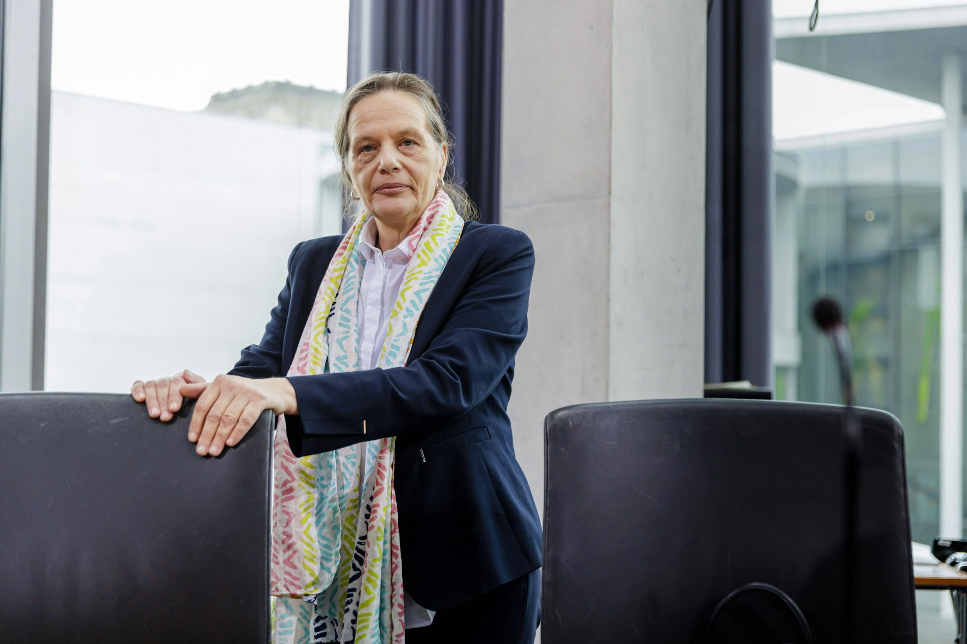 Bundeswahlleiterin Dr. Ruth Brand posiert für ein Foto, hat die Hände auf eine Stuhllehne gelegt.