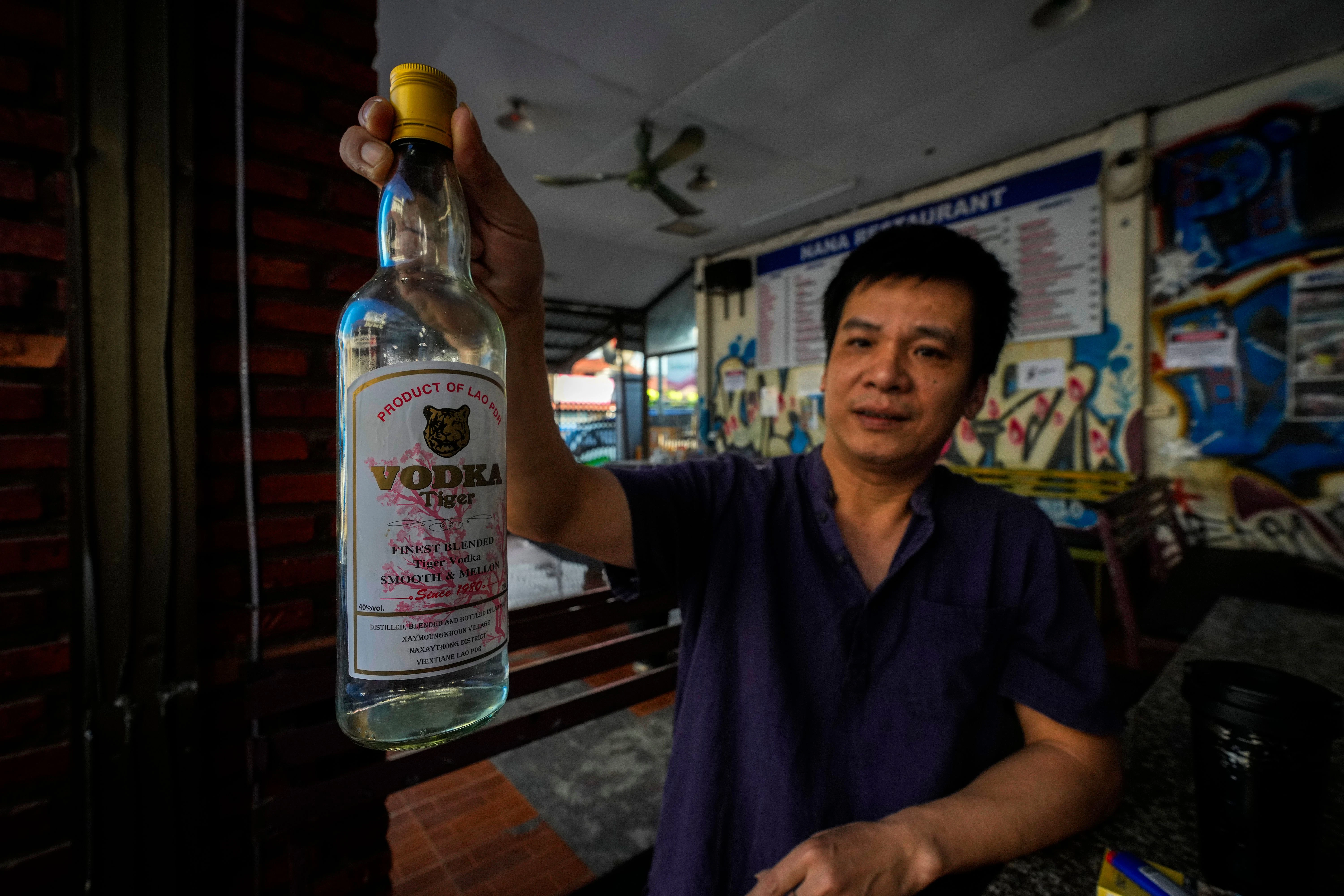 Duong Duc Toan, der Manager des Nana Backpack Hostels, zeigt in der Bar des Hostels in Vang Vieng eine Flasche Wodka.