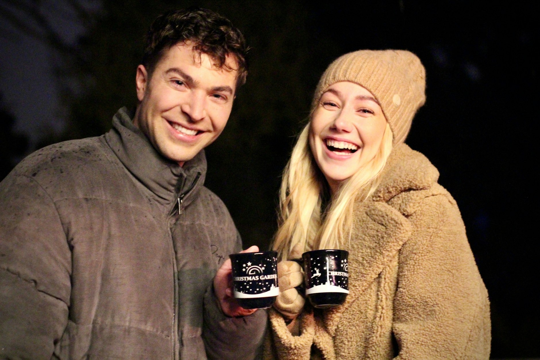 Schlagerstar Julian David und die Unternehmerin Annalena Kaiser, Teil der fröhlichen Gruppe, genießen gemeinsam die zauberhafte Stimmung im „Christmas Garden Berlin“. „Stößchen“ mit Punsch und Glühwein!