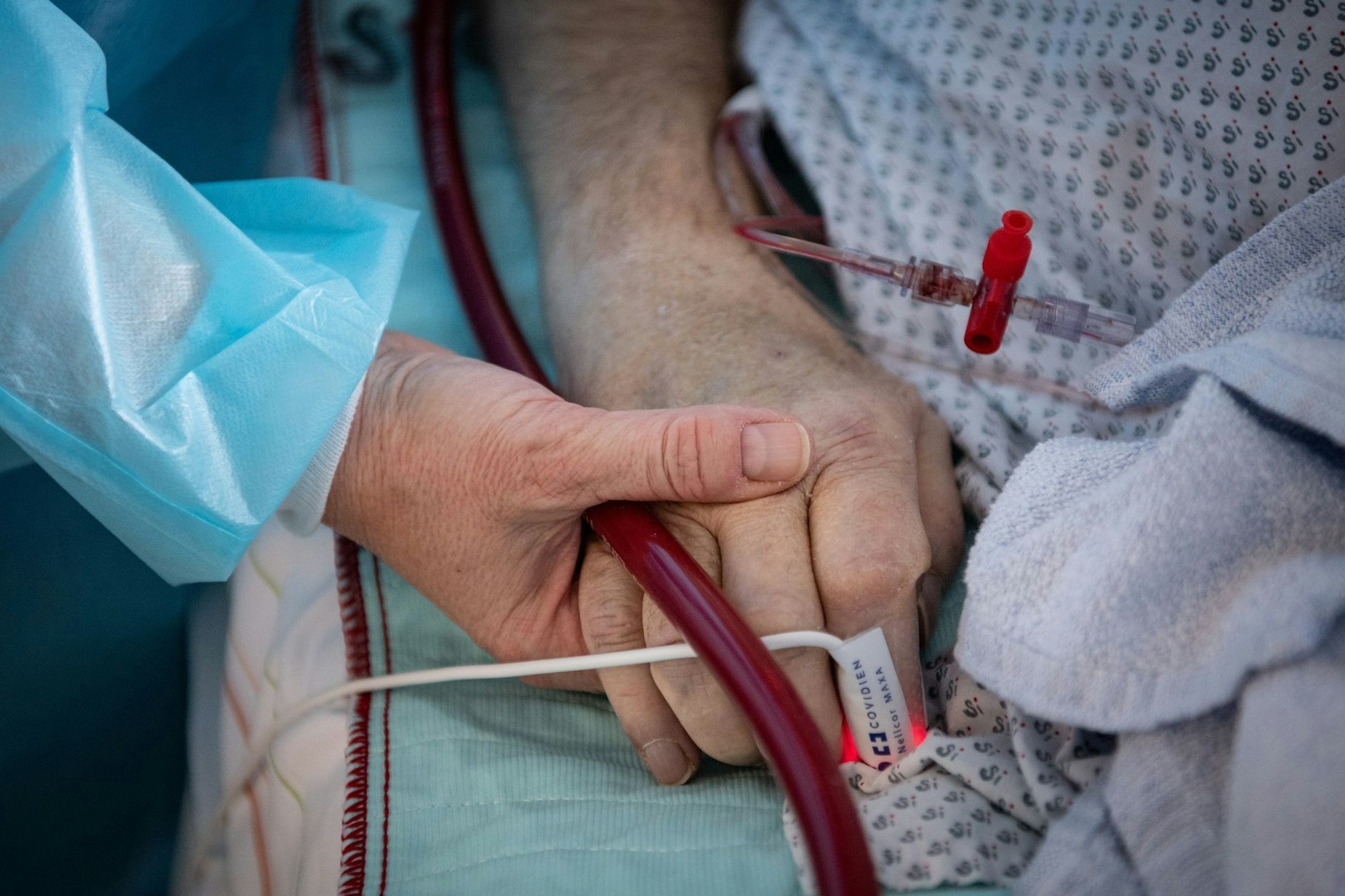 Eine Intensivpflegekraft hält einem Patienten die Hand.