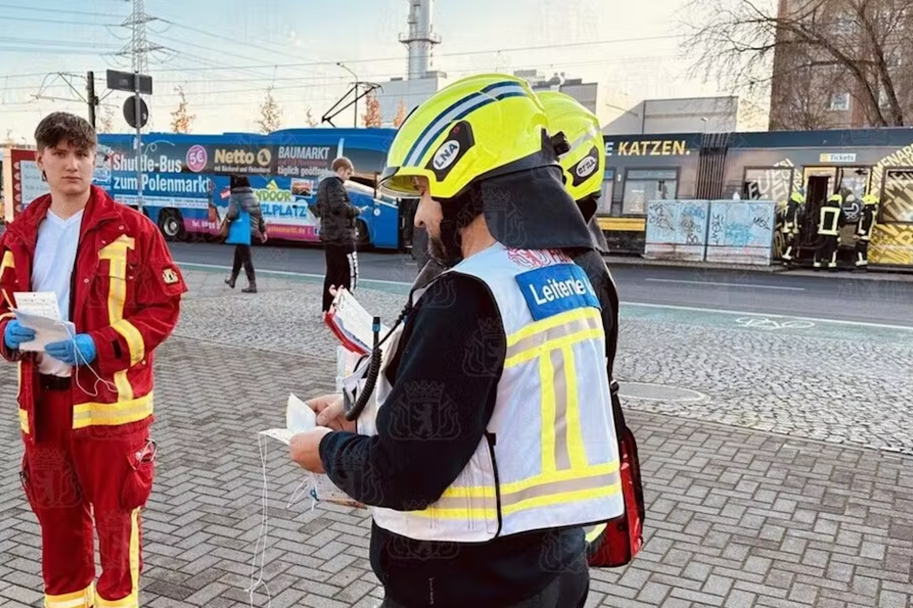 Rettungskräfte an der Unfallstelle in der Allee der Kosmonauten. Straßenbahn und der blaue Reisebus stehen nebeneinander.