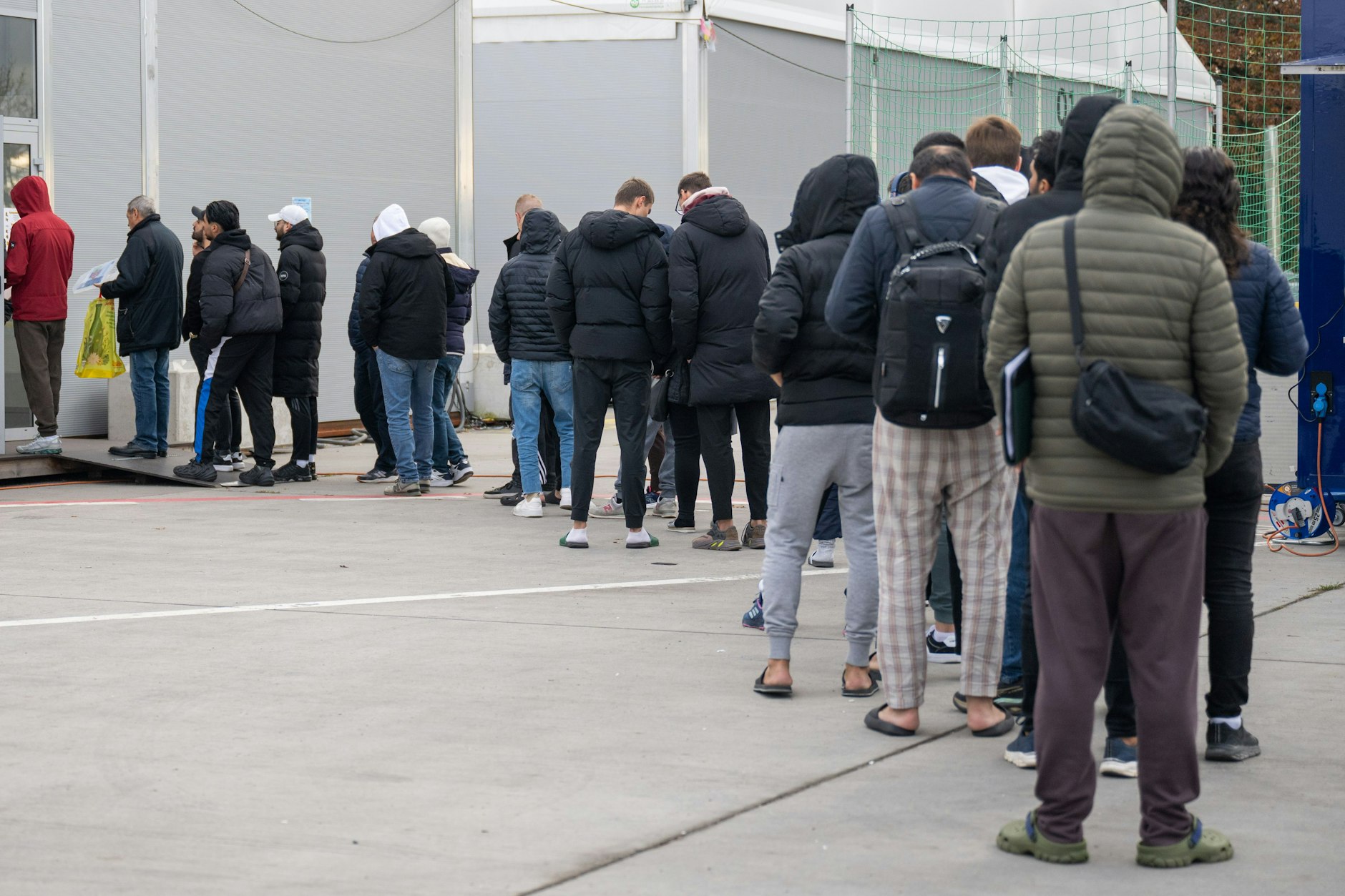Am ehemaligen Flughafen Tegel stehen Flüchtlinge vor einer Leichtbauhalle. Um das Ankunftszentrum zu entlasten, sollen neue Großunterkünfte in Berlin entstehen.