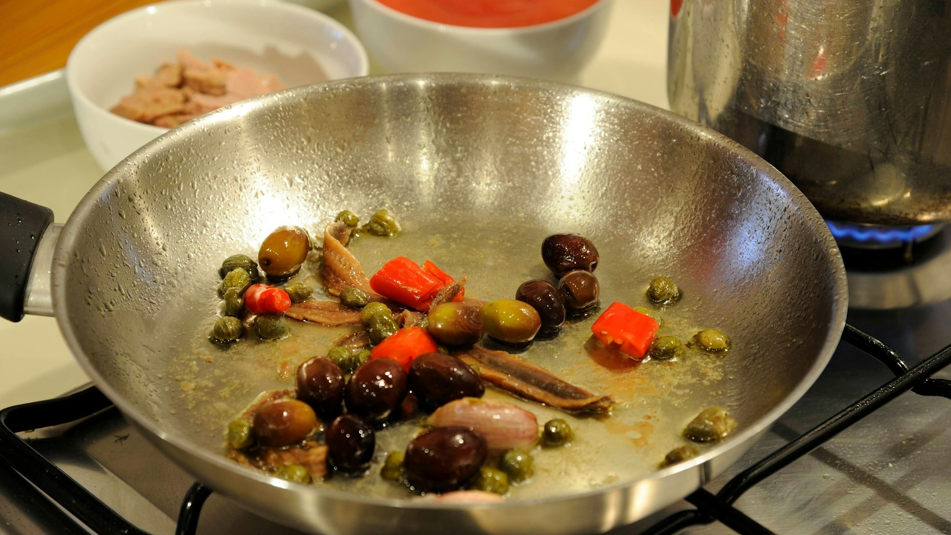 Knoblauch, Sardellen, Chili, Kapern und Oliven werden für die Spaghetti alla puttanesca in gutem Olivenöl angebraten.