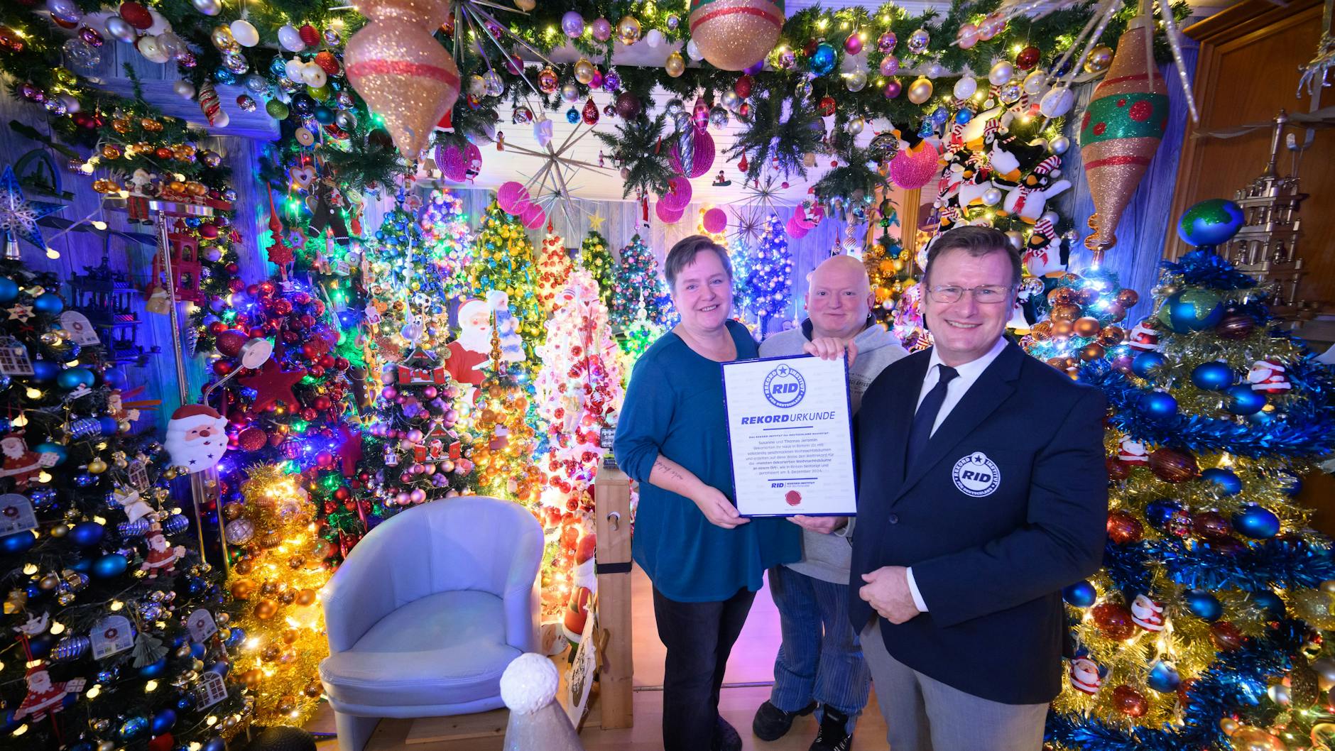 Susanne und Thomas Jeromin mit Olaf Kuchenbecker (r.) vom Rekord-Institut für Deutschland inmitten von 600 Weihnachtsbäumen in ihrem Haus im Landkreis Schaumburg.