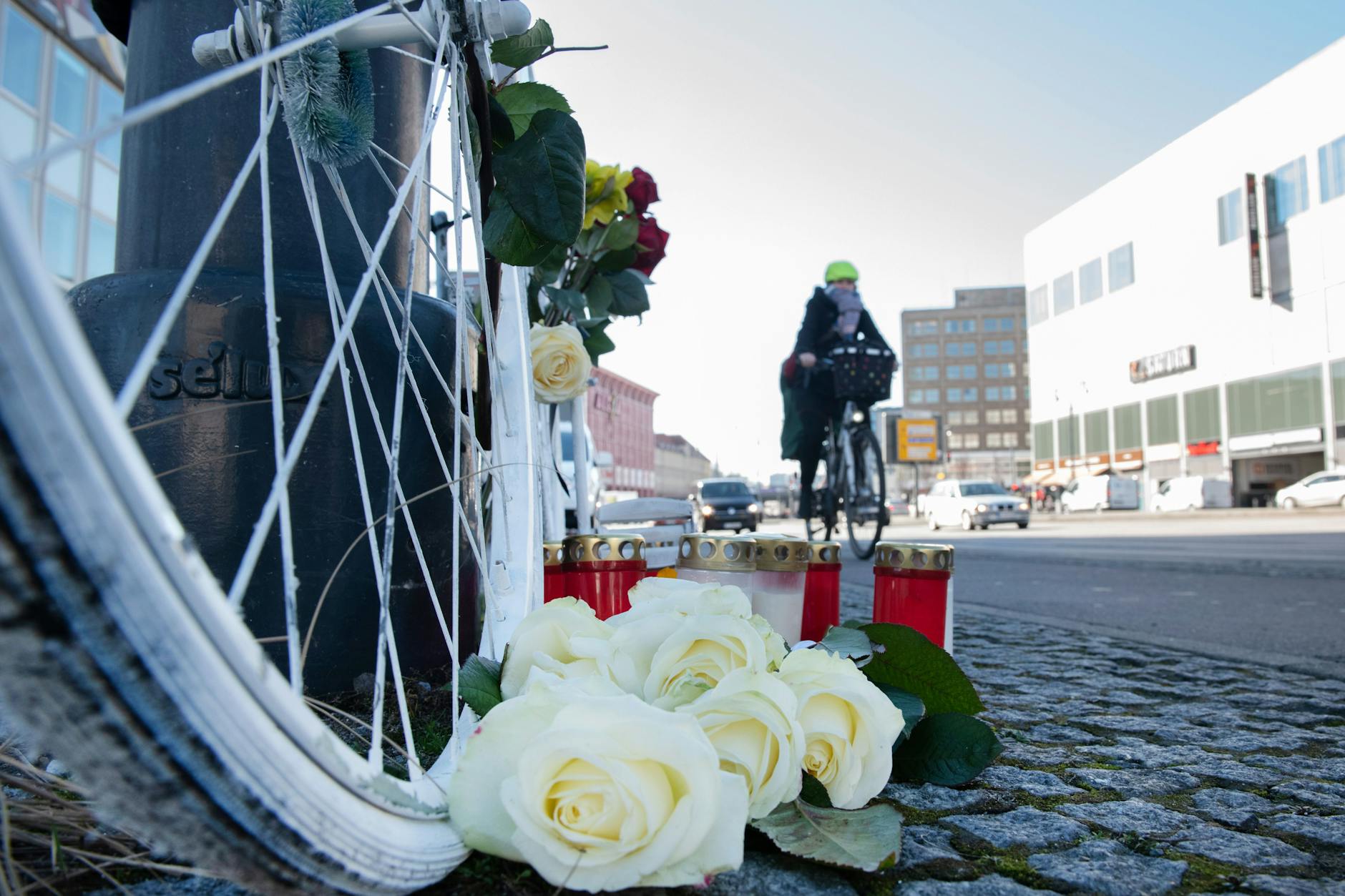 Blumen und Kerzen sind vor einem weißen Geisterrad an der Stelle eines tödlichen Radunfalls in Berlin-Mitte aufgestellt.