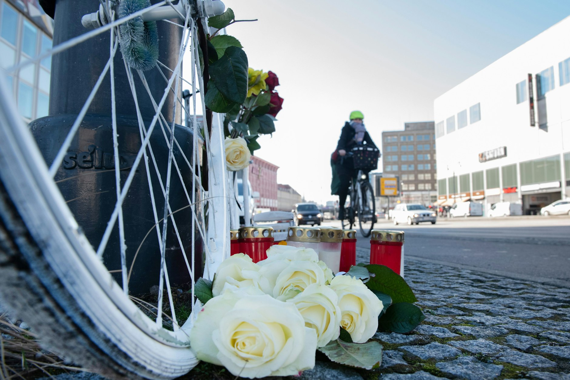 Blumen und Kerzen sind vor einem weißen Geisterrad an der Stelle eines tödlichen Radunfalls in Berlin-Mitte aufgestellt.