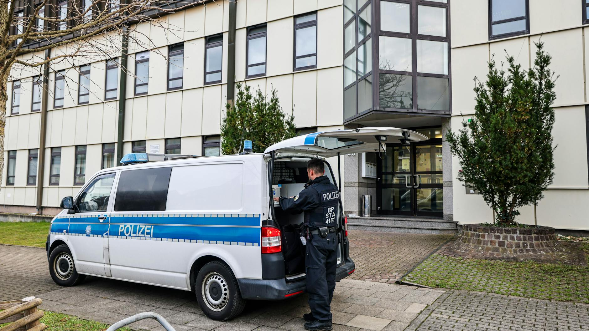Ein Polizeibeamter der Bundespolizei steht an einem Polizeiauto vor einer Flüchtlingsunterkunft in Essen. Auch hier kam es am Morgen zu einem Einsatz.