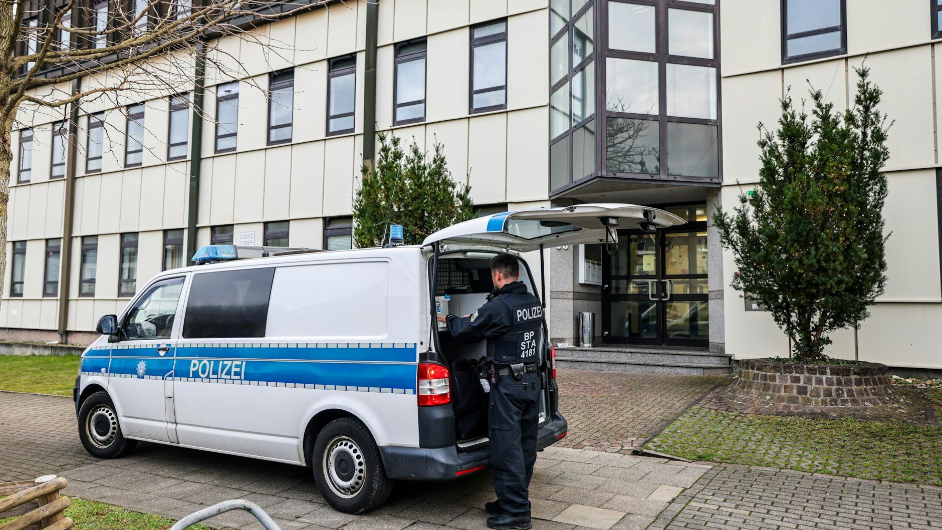 Ein Polizeibeamter der Bundespolizei steht an einem Polizeiauto vor einer Flüchtlingsunterkunft in Essen. Auch hier kam es am Morgen zu einem Einsatz.