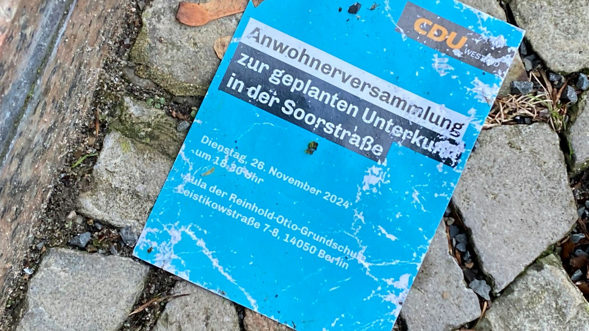 Vor dem Bürogebäude liegt noch eine Einladungskarte für die Anwohnerversammlung zum geplanten Flüchtlingsheim.