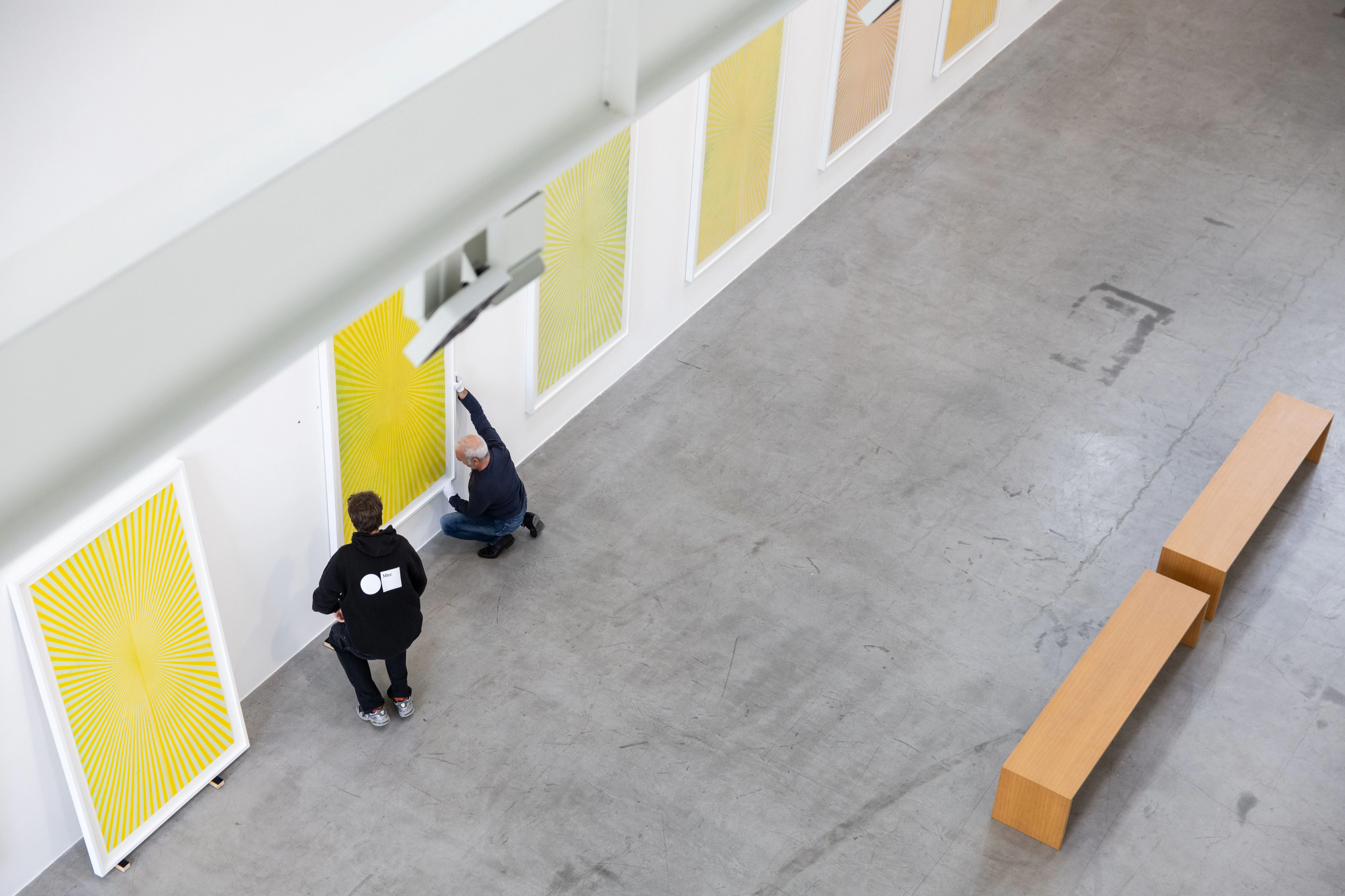Mitarbeiter bringen Bilder des Künstlers Mark Grotjahn an einer Wand der Galerie Max Hetzler an.