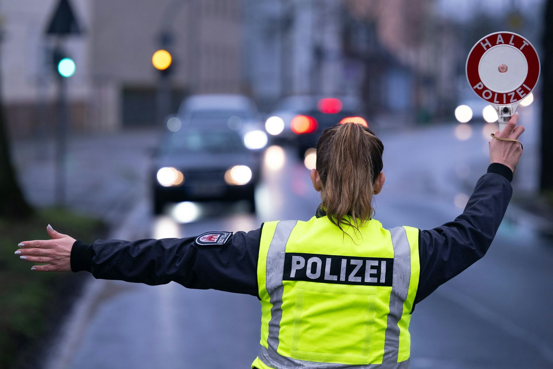 Eine Polizistin winkt während einer Verkehrskontrolle an der Berliner Straße mit einer Polizeikelle ein Auto von der Straße auf den Kontrollplatz.