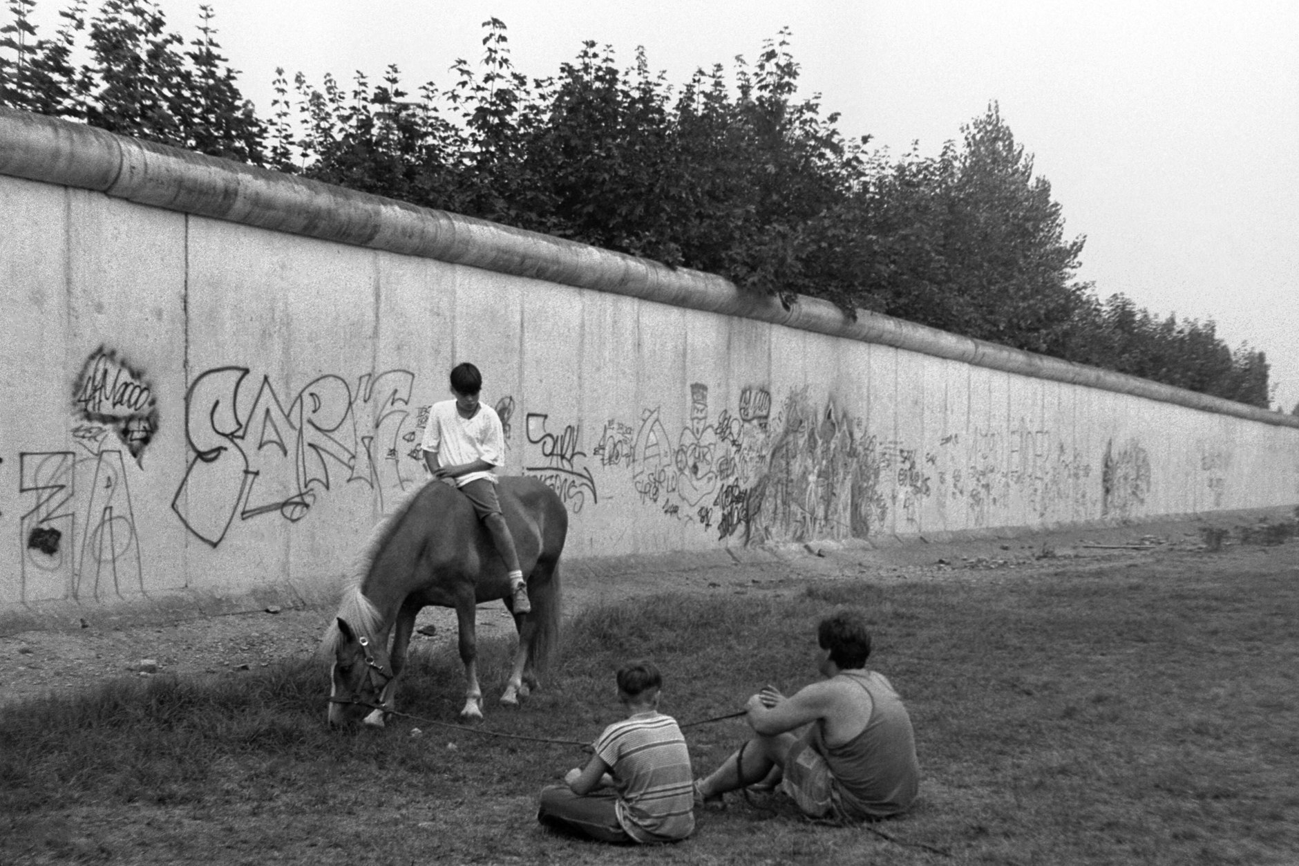 Jugendliche spielen 1990 auf dem ehemaligen Todesstreifen der Mauer. Die Erinnerung an die DDR polarisiert auch noch 34 Jahre nach ihrem Ende.