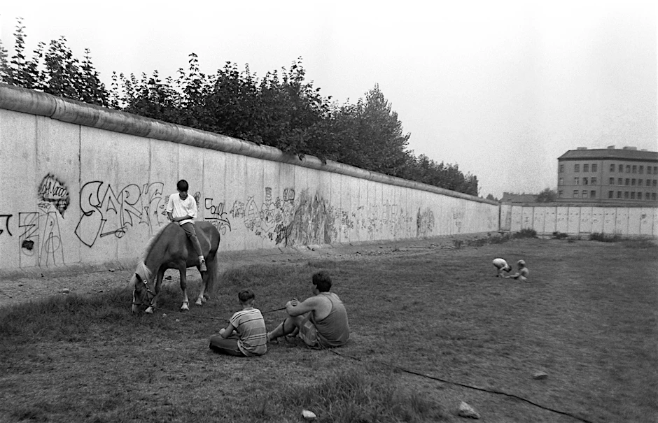 Jugendliche spielen 1990 auf dem ehemaligen Todesstreifen der Mauer. Die Erinnerung an die DDR polarisiert auch noch 34 Jahre nach ihrem Ende.
