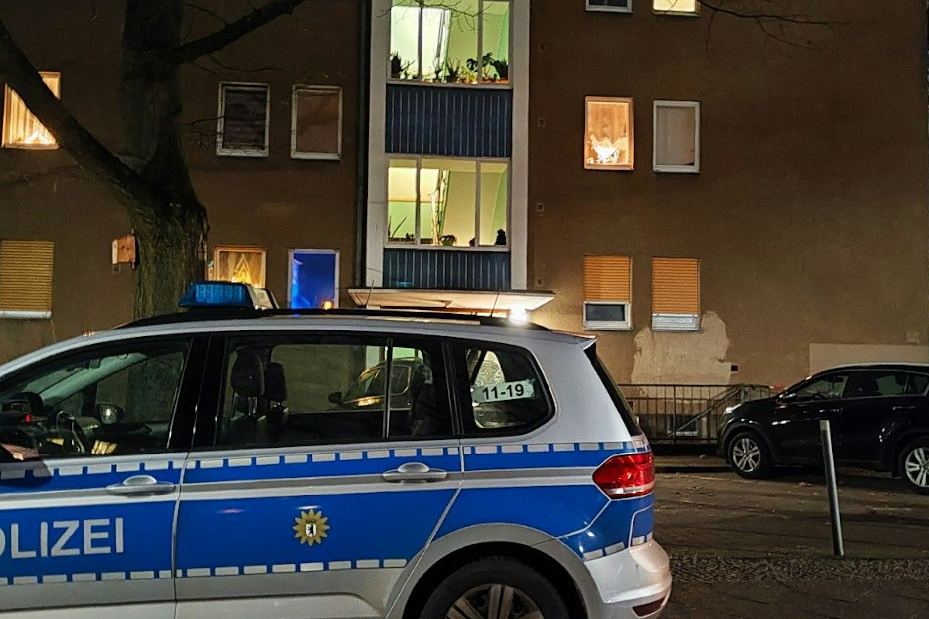 Ein Einsatzwagen der Berliner Polizei steht vor dem Wohnhaus in Tegel. Eine Frau stürzte hier vom Balkon - es wird wegen eines versuchten Tötungsdelikts ermittelt.