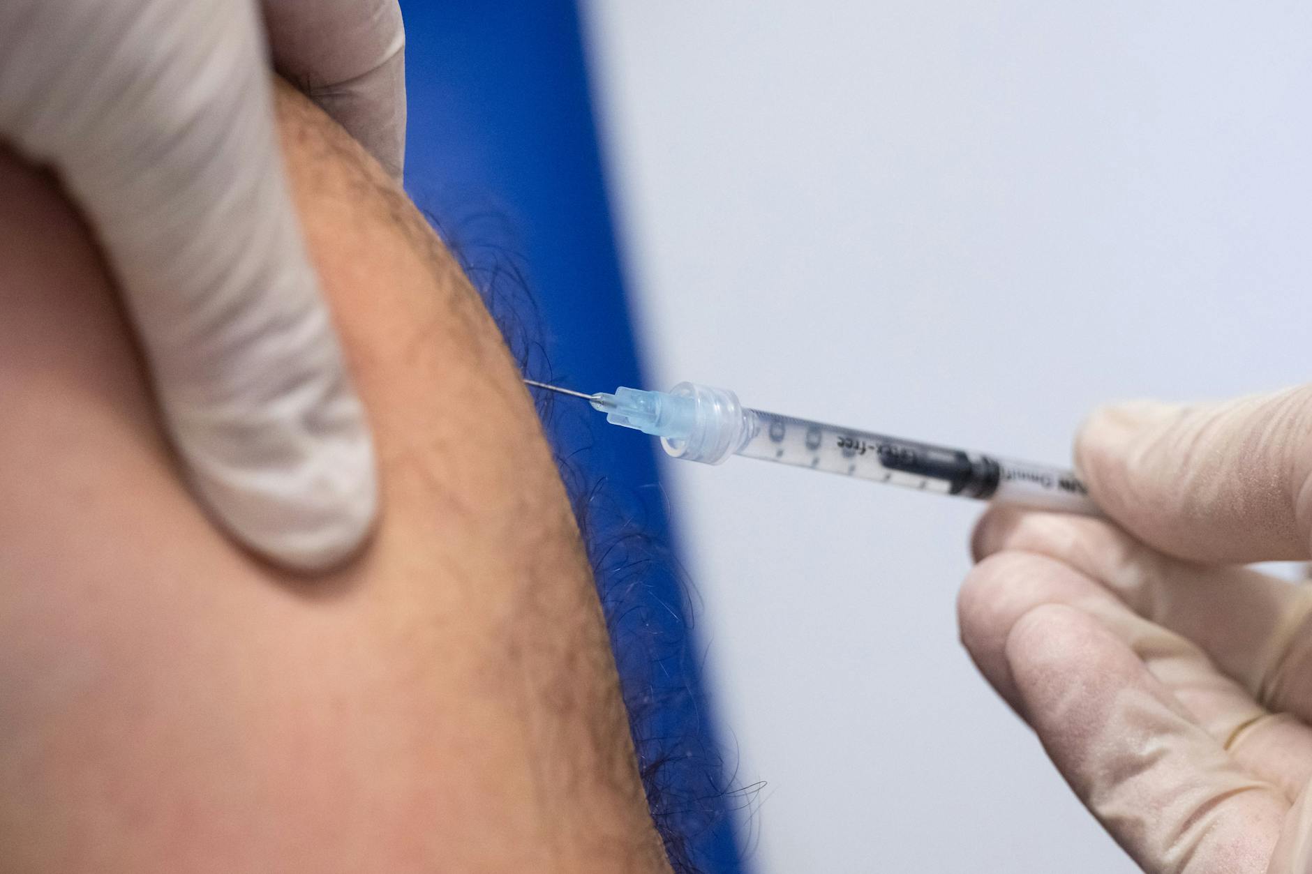 Ein Klinik-Mitarbeiter impft einen Mann gegen Affenpocken.