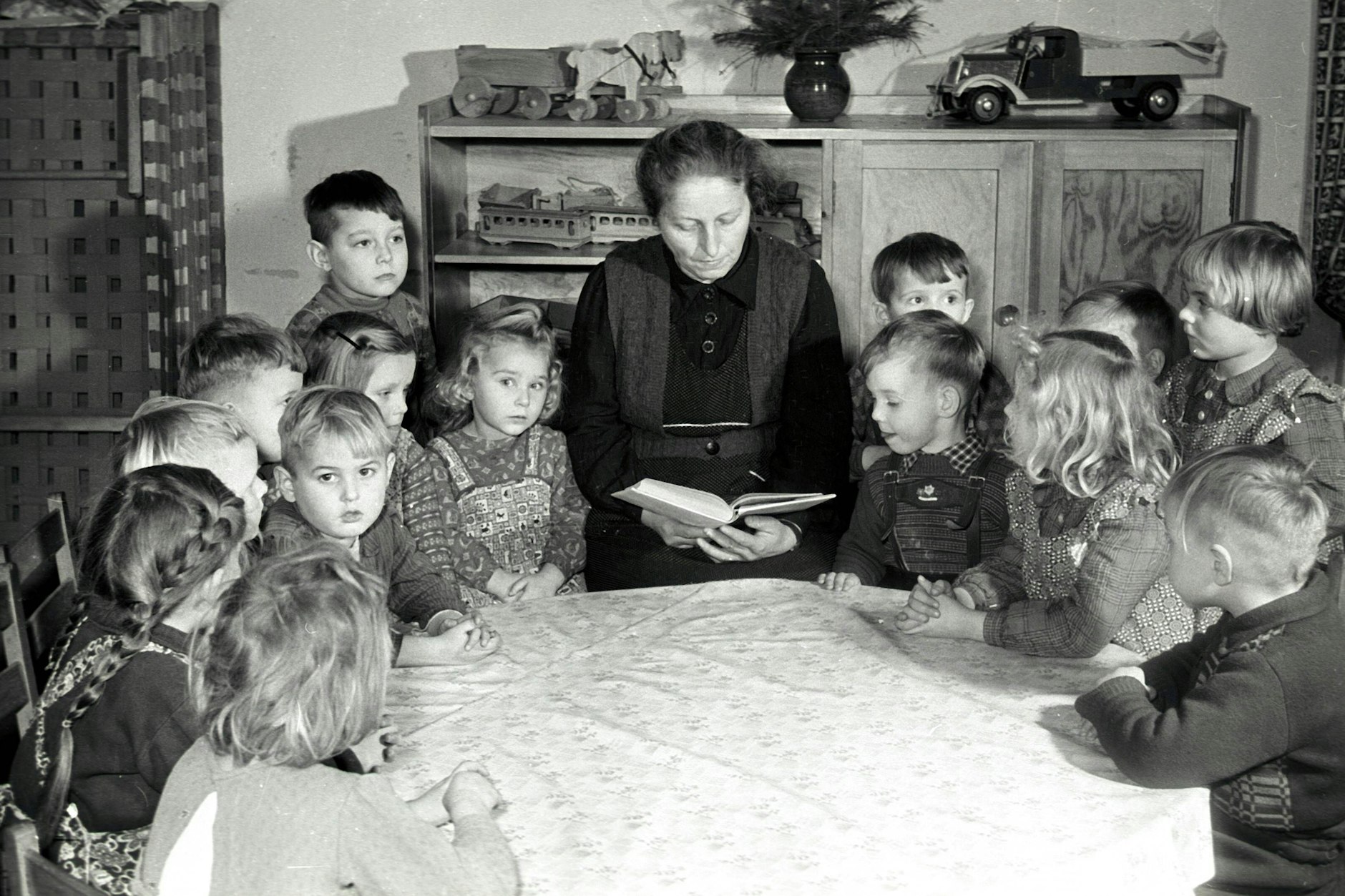 Einer Erzieherin liest Mädchen und Jungen in einem DDR-Kindergarten aus einem Buch vor (1957). Viele der schönsten Geschichten für Kinder entstanden in den 50er- und 60er-Jahren, sind bis heute beliebt.